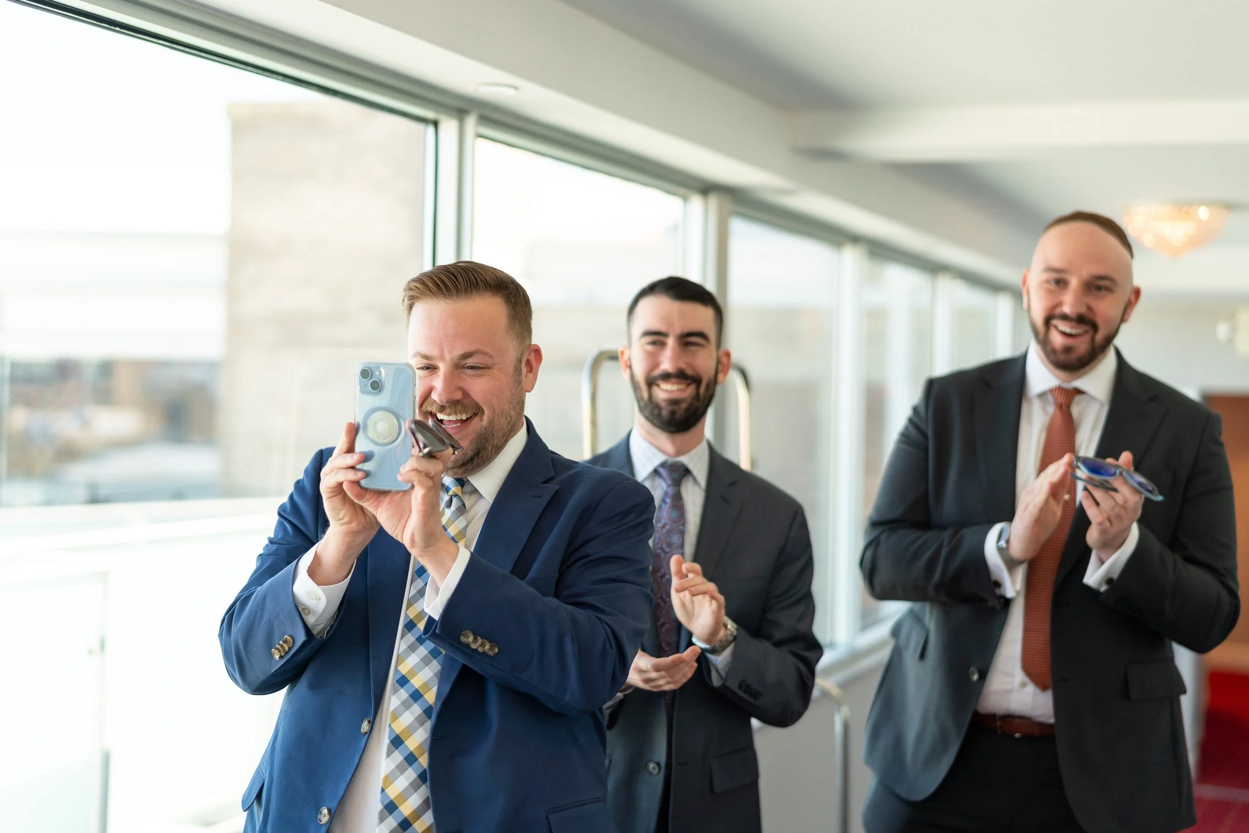 Two grooms greeting guests on the wedding day Top of the Town wedding photos