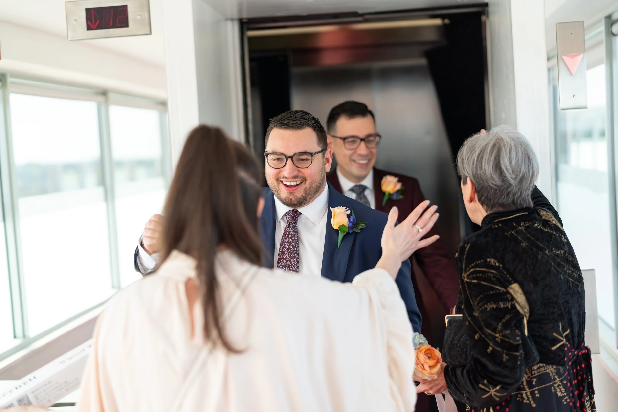 Two grooms greeting guests on the wedding day Top of the Town wedding photos