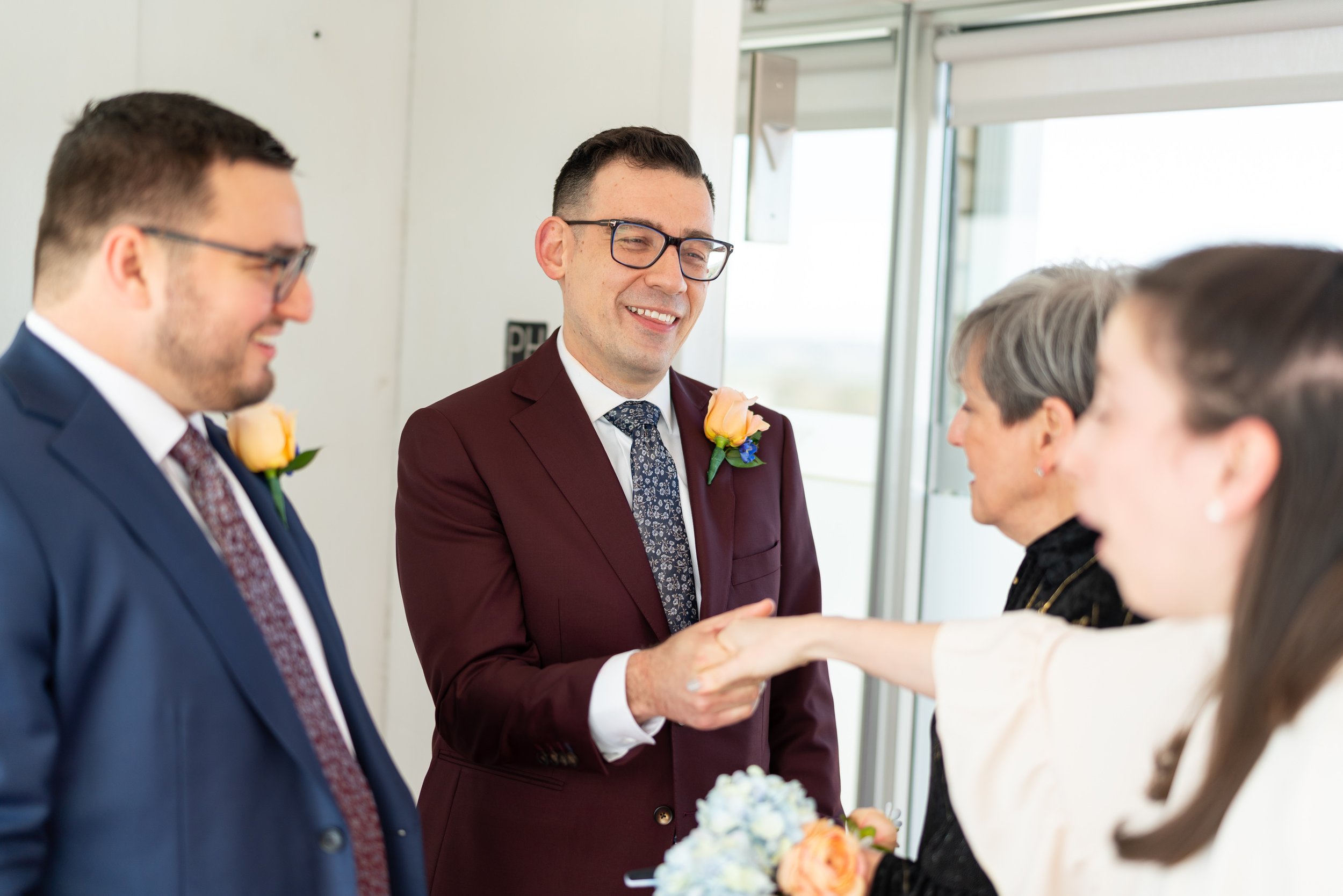 Two grooms greeting guests on the wedding day Top of the Town wedding photos