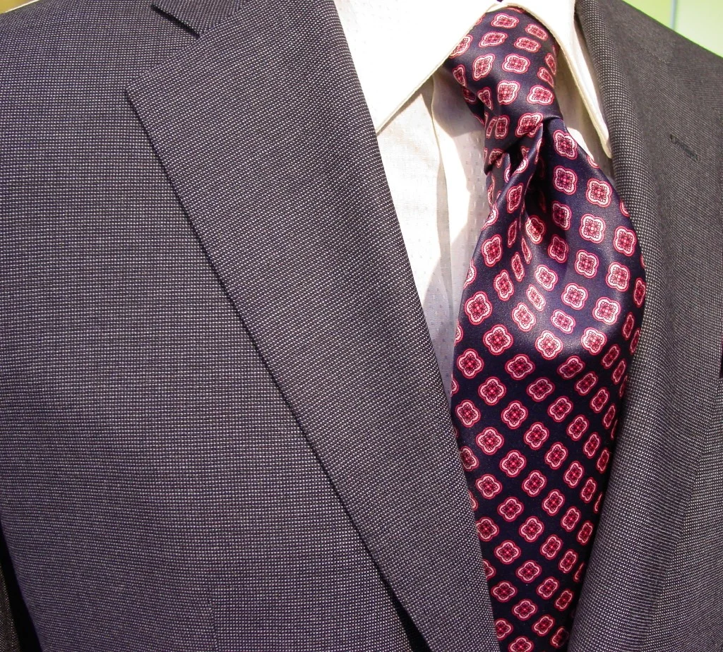 Grey single breasted interview suit with small pattern tie.