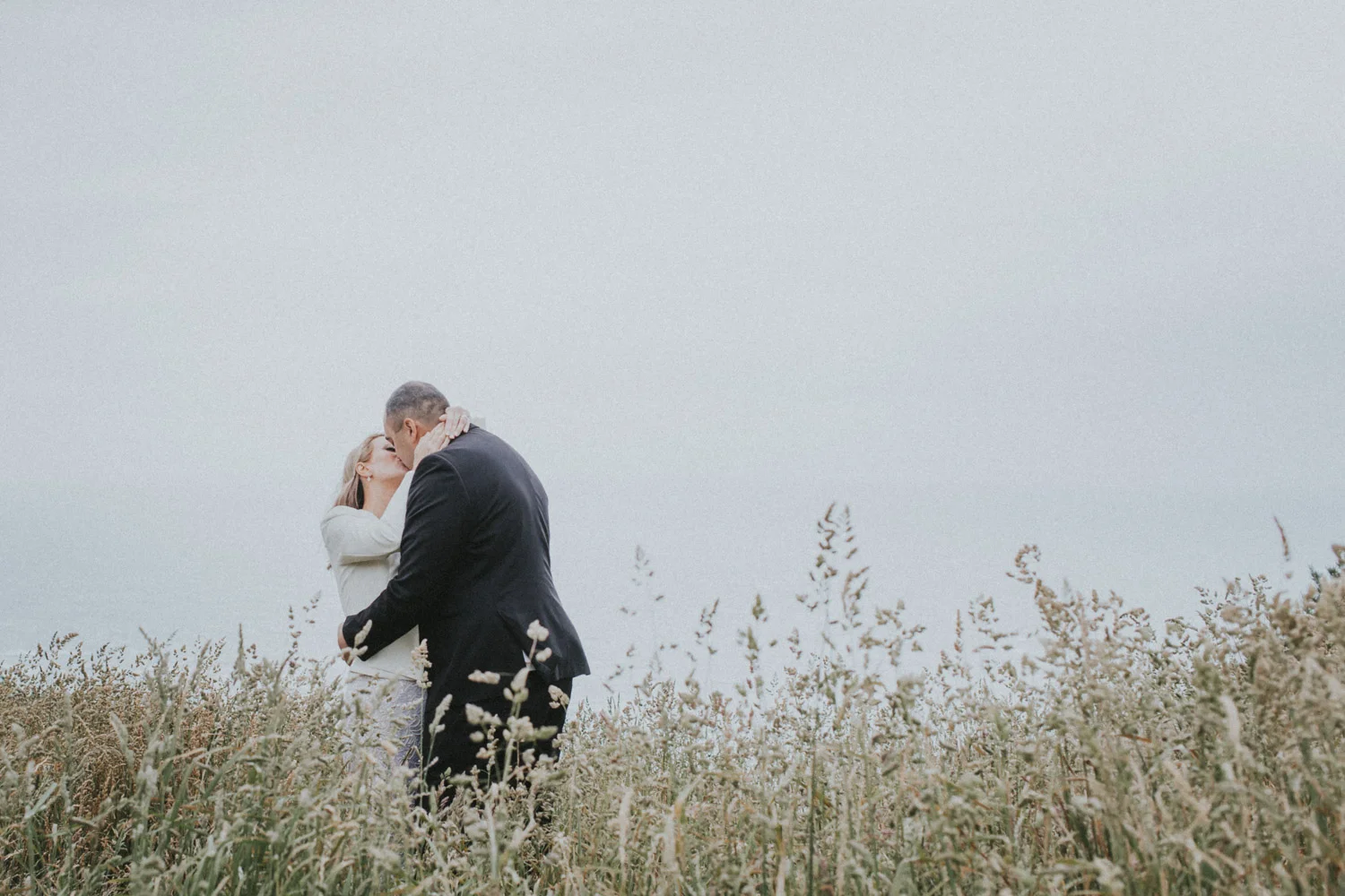 Bride and Groom kiss in the long grass at Boomrock, Wellington wedding venue
