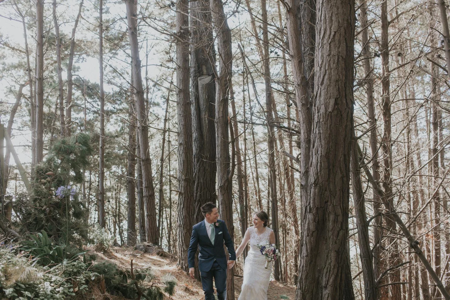 Newly weds walking through forest holding hands