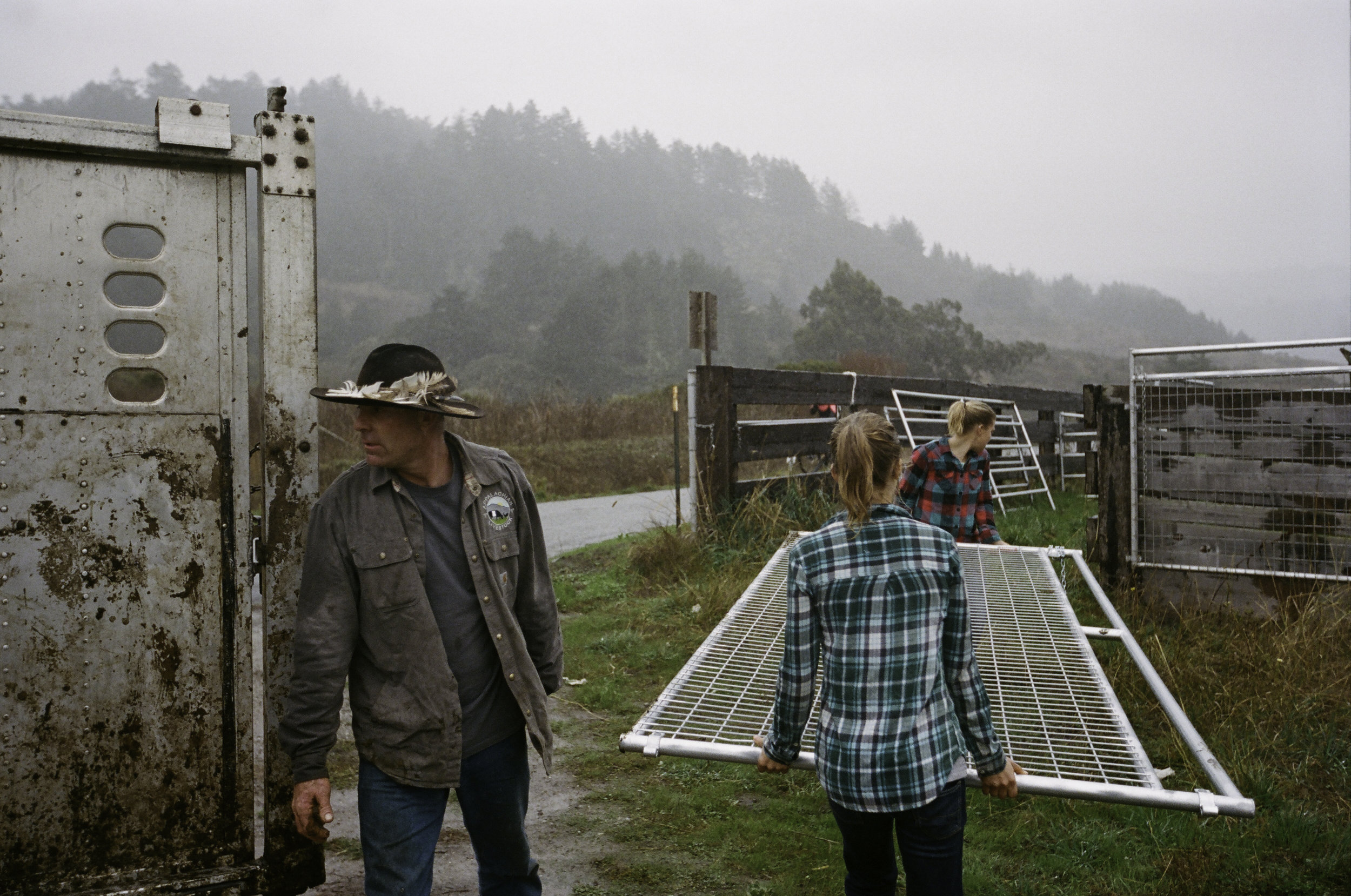  Erik, Johanna, and Ruth work to quickly unload fencing in the rain. -&nbsp;San Gregorio, CA 
