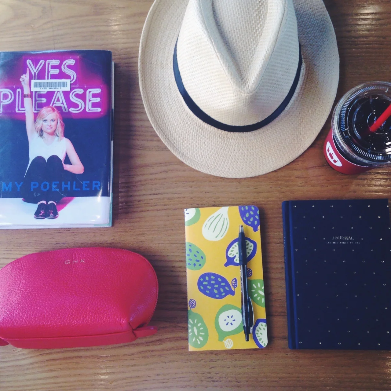 Essentials for a cafe trip: current read- Amy Poehler's Yes Please, makeup bag, journals, pen, panama hat, and an iced americano. 