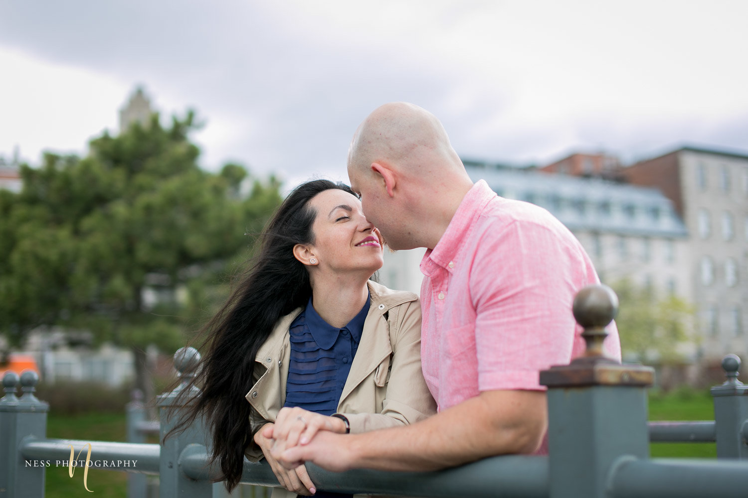 couple kissing on top of bridge in old port of montreal during their pre wedding engagement photos
