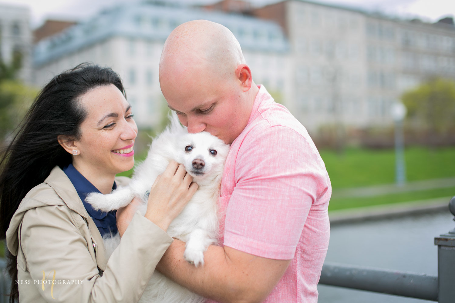 couple holding a dog and laughing during their engagement photoshoot in old port of montreal