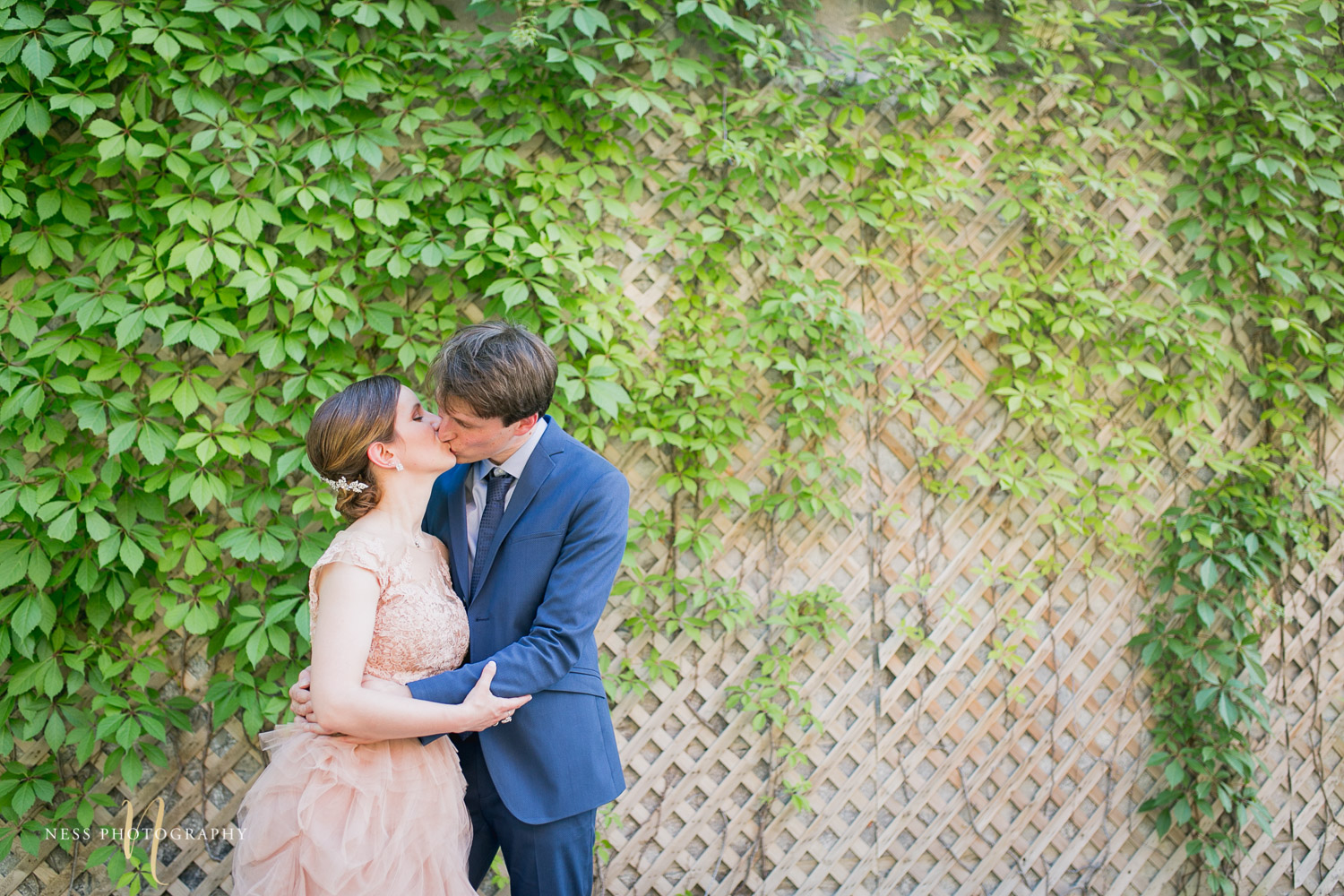 bride and groom kissing in front of vine wall during elopement wedding photos