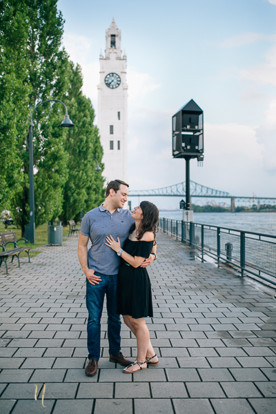 just engaged couple posing in front of old montreal clock tower after surprise proposal