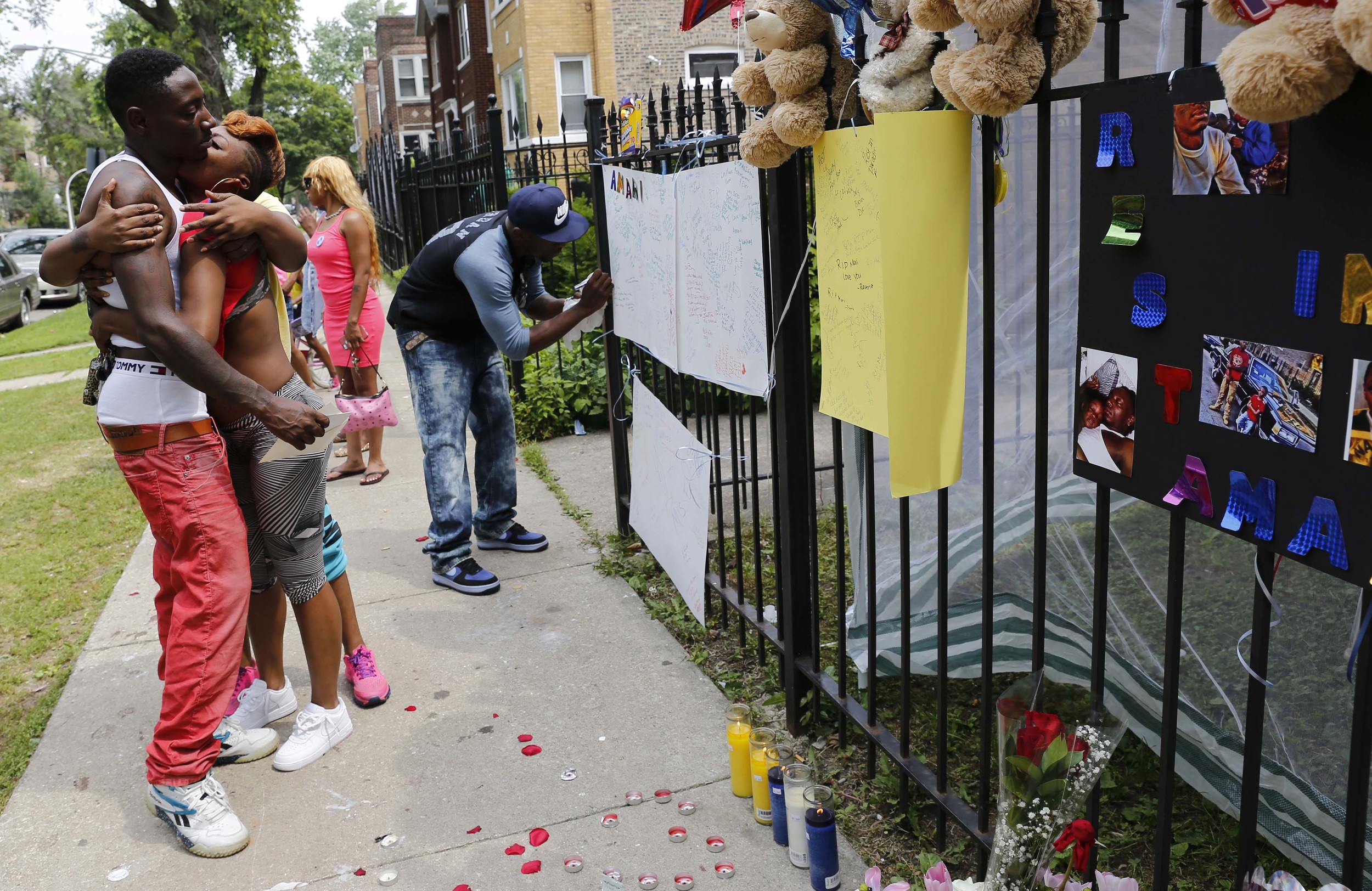 Antonio Brown, left, is embraced by a community member in front of a make-shift memorial, for Brown's 7-year-old son Monday, July 6, 2015, in Chicago. Authorities say 7-year-old Amari Brown, was among three people who were shot and killed overnight