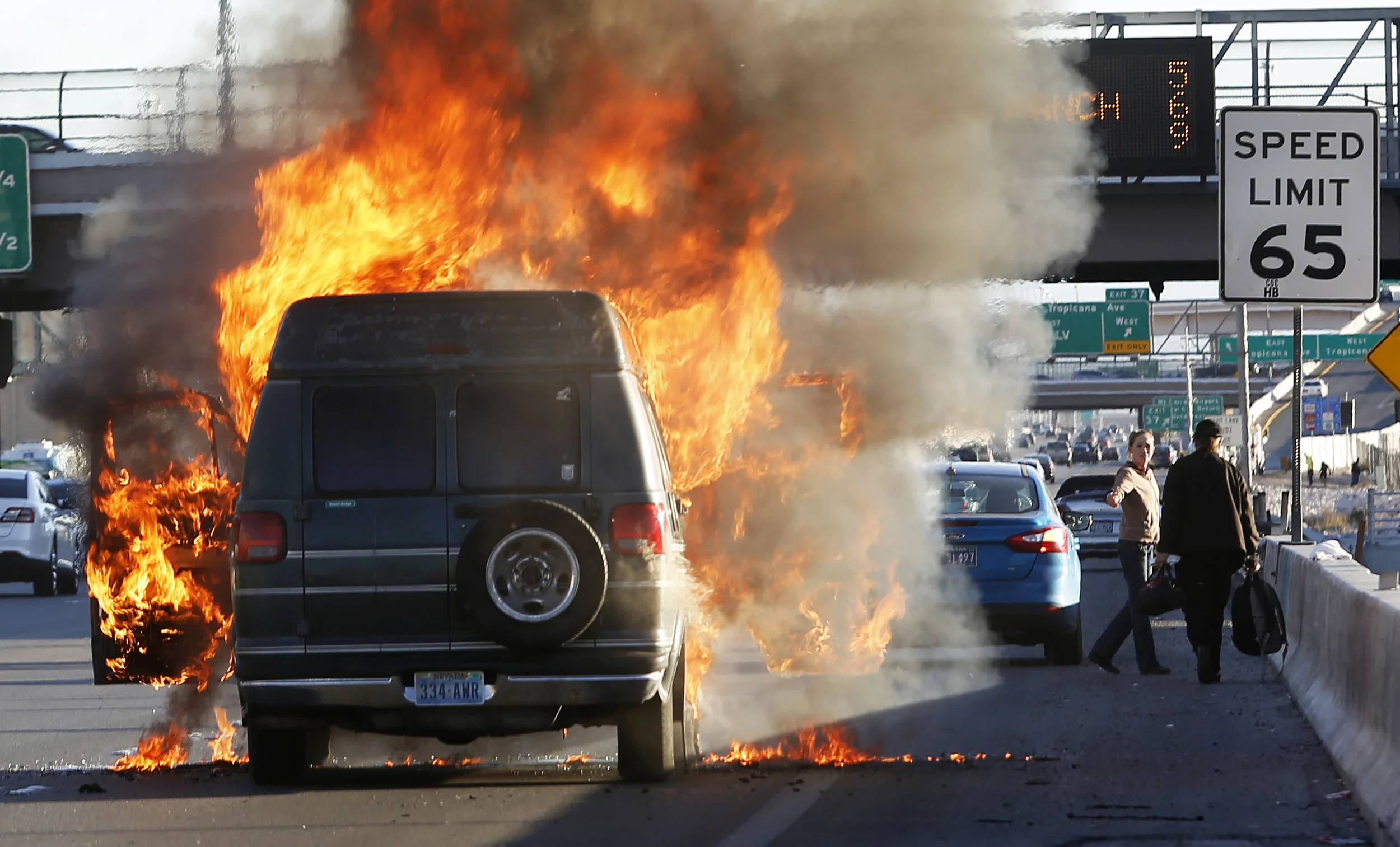  A passenger flees from his vehicle while it is engulfed in flames on I-15 south near exit 37 on Saturday, Jan. 28, 2017, in Las Vegas. 