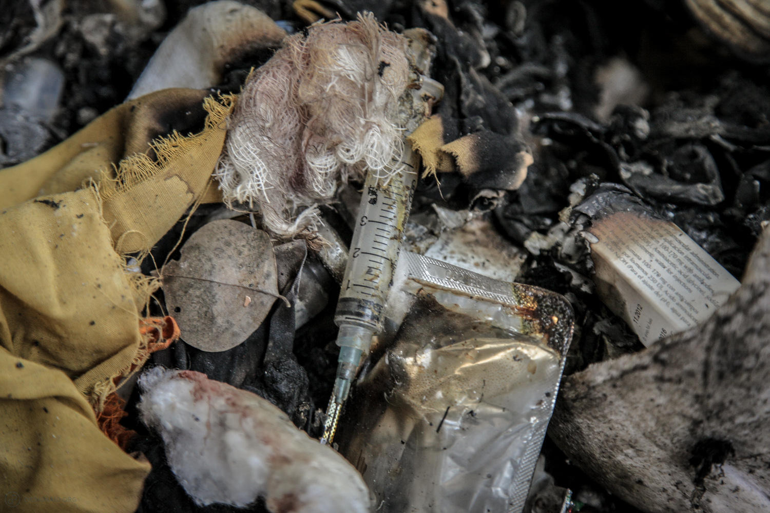 One of thousands of used needles poking out of the waste pile