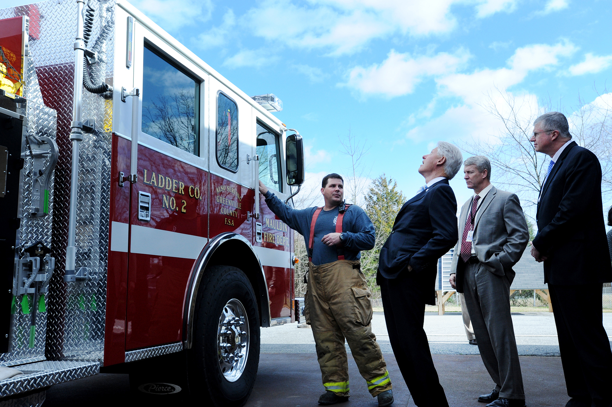 President Bill Clinton, center, looks up at a Mauldin Fire Department truck while being given a tour of the firefighting program at the Golden Strip Career Center in Mauldin, S.C., by instructor Jim Deese, left.