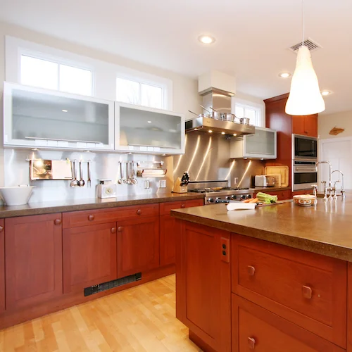 Metal cabinets with glass inserts have a modern vibe while the cherry cabinets and concrete counters add an eclectic aesthetic.