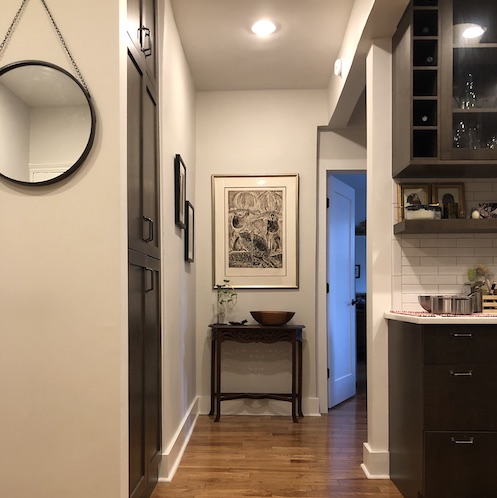 Renovated foyer shows the open kitchen and in-set pantry across the hallway.