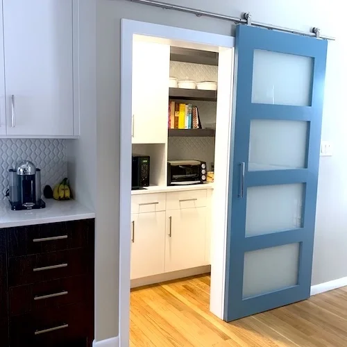 Modern kitchen with a walk-in pantry featuring a frosted glass panel sliding door.
