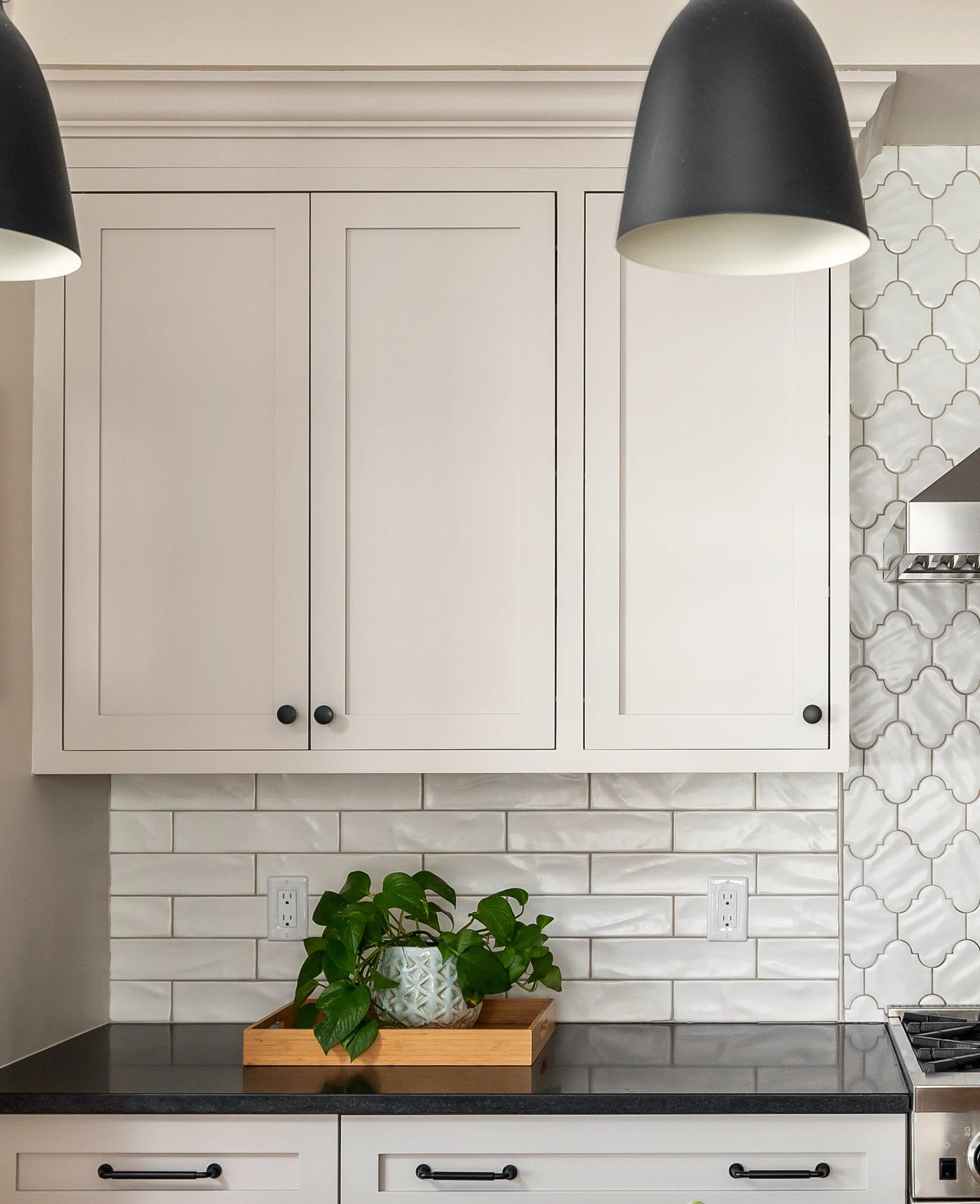 The black matte pulls and knobs complement the black pendants and dark countertop.