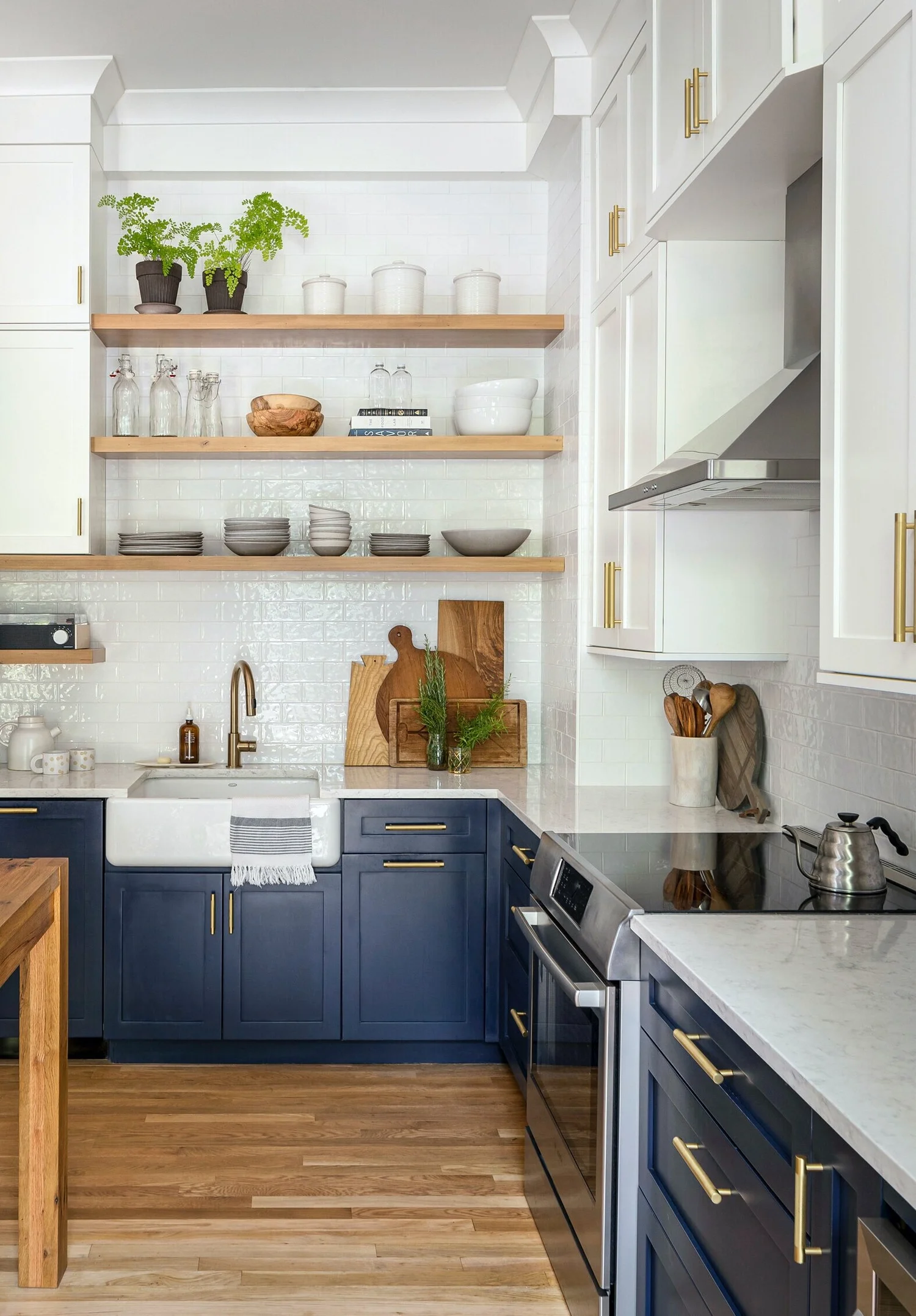 Warm brushed brass pulls in a range of sizes pop against the navy and white cabinetry.