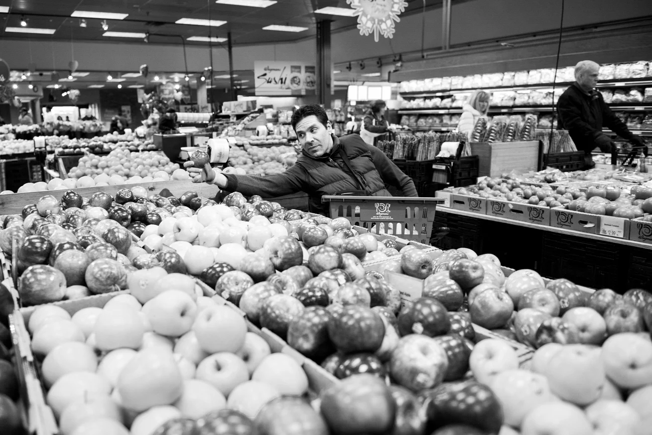 David struggles to reach the apple he wants at the local Wegmans. David often struggles to get things because of his disability, but has found alternative devices to help him