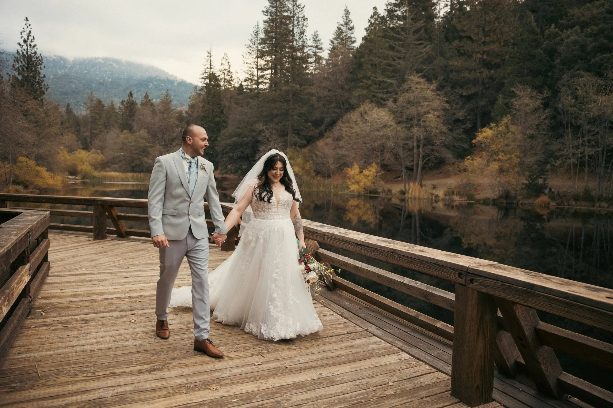 Couple walking hand in hand on a wooden bridge over a lake in Idyllwild CA (Copy)