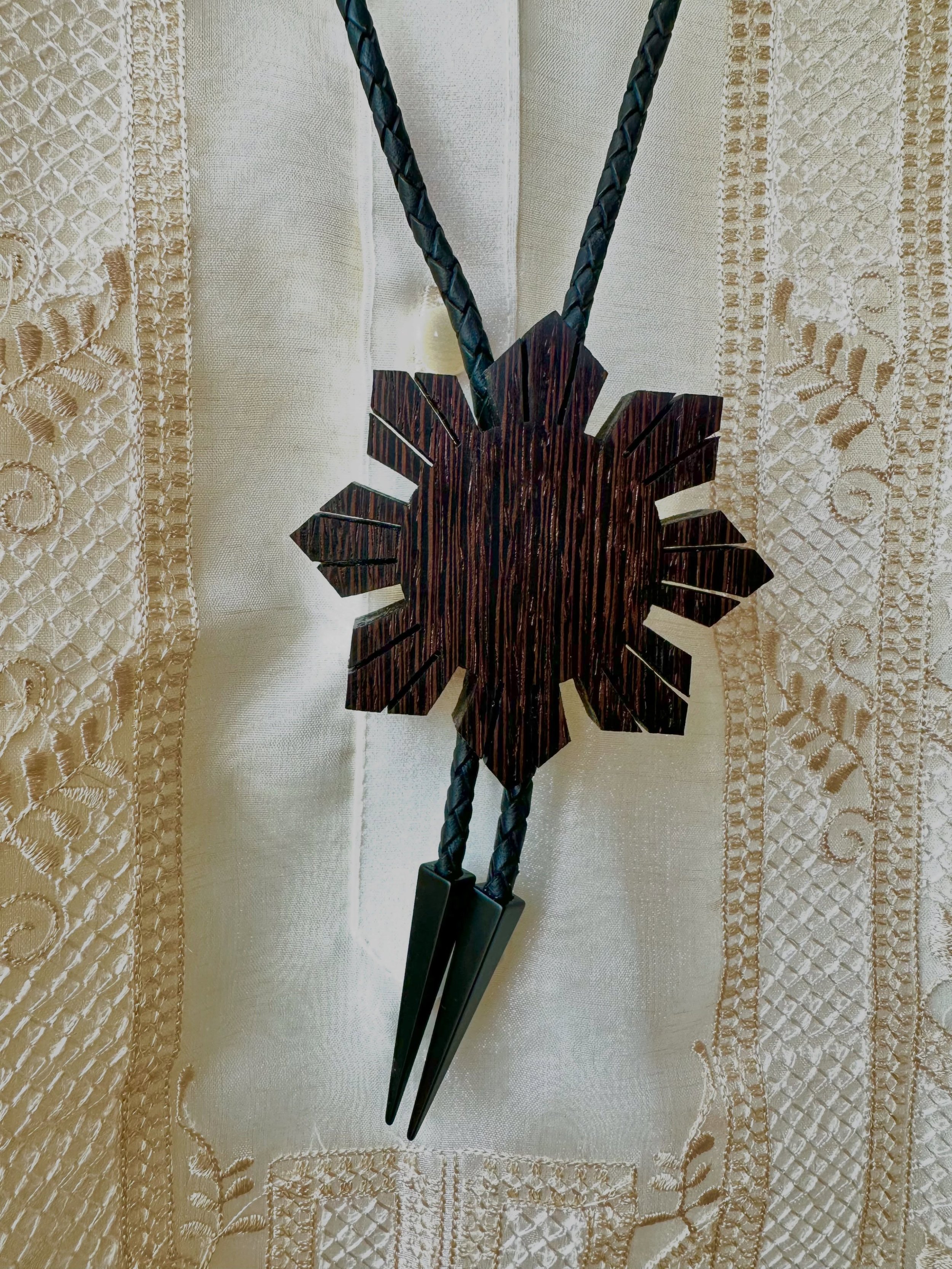 3&rdquo; Araw Bolo in Wenge with black leather cord and black triangle tips. Fun fact: Wenge has a janka hardness rating of ~1930 foot-pounds, which is more than three times harder than your typical 2x4 (Douglas Fir, ~600 lbf). It&rsquo;s one of the 
