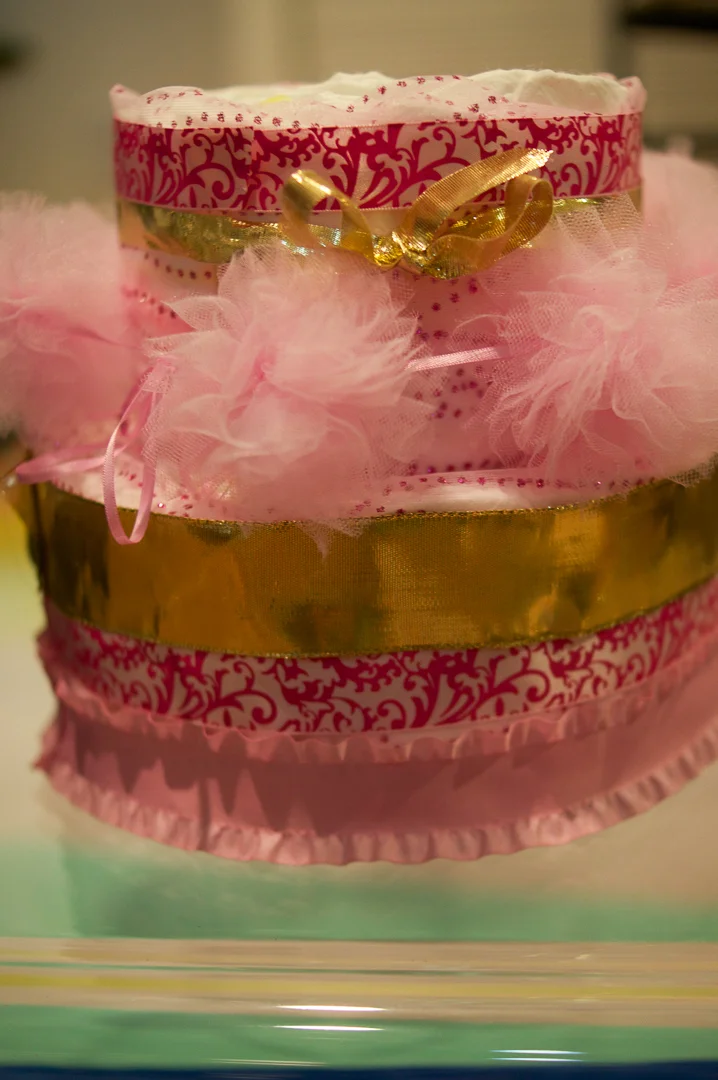 I chose to put just one ribbon on the top layer and tied a golden ribbon around it as a bow. The pink fluffy balls decorate the top of the base layer.