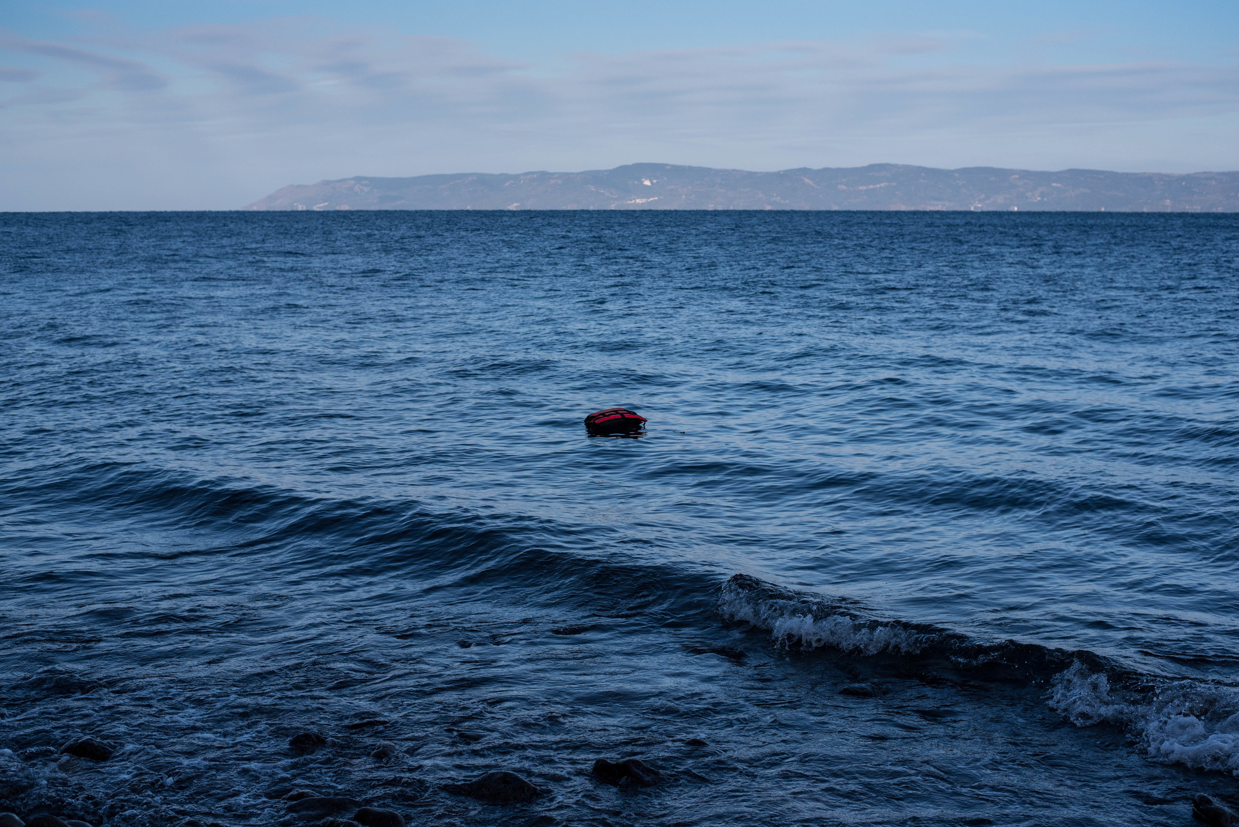  A lone life jacket drifts on the water near the shores of Lesvos, Greece. Most of the life jackets sold to refugees in Turkey are not actually life-saving; instead they're made from cheap pieces of foam and misleadingly display Japanese brand names 