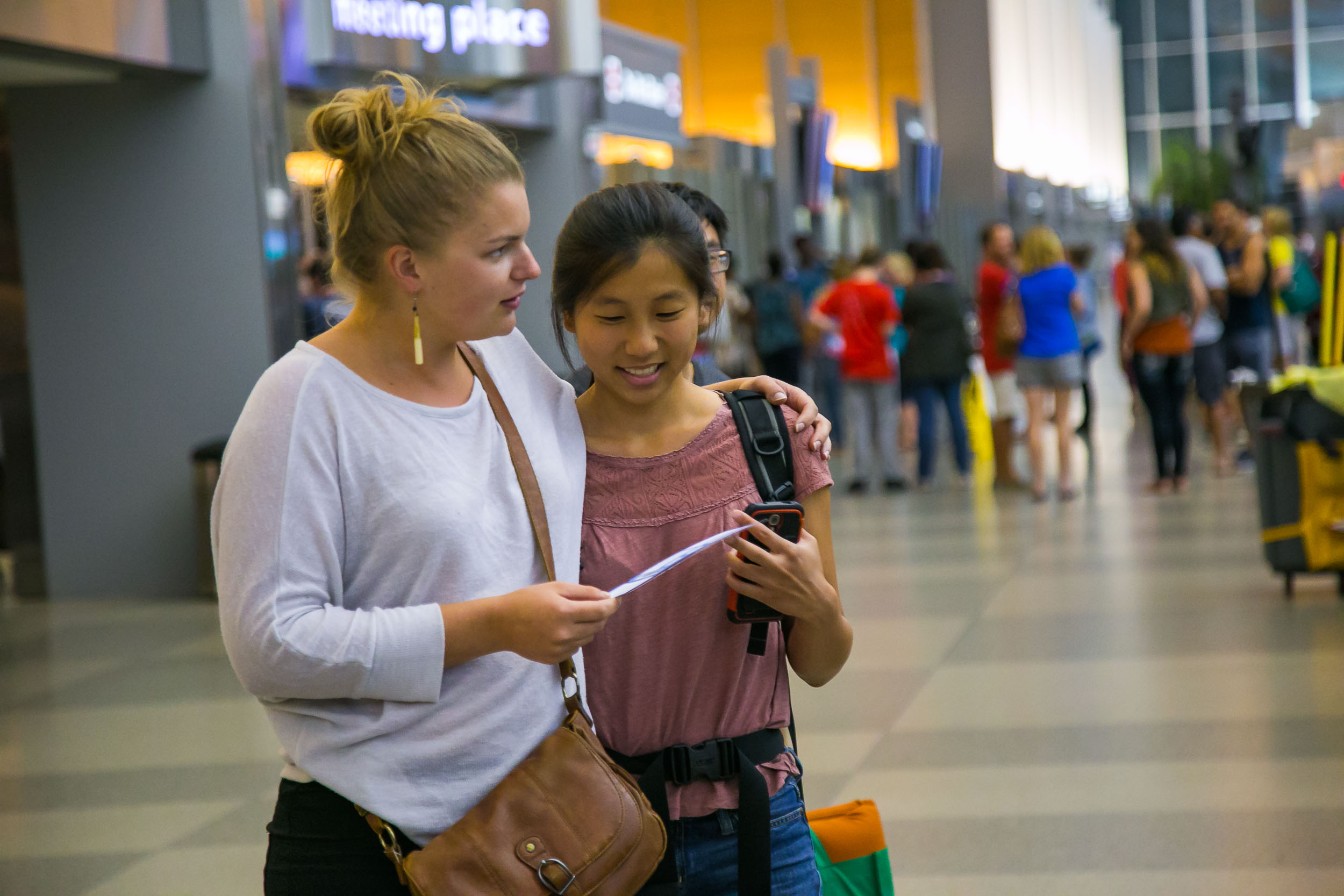 Raleigh Engagement Photographer | G. Lin Photography | Woman explaining plan to friend at airport terminal