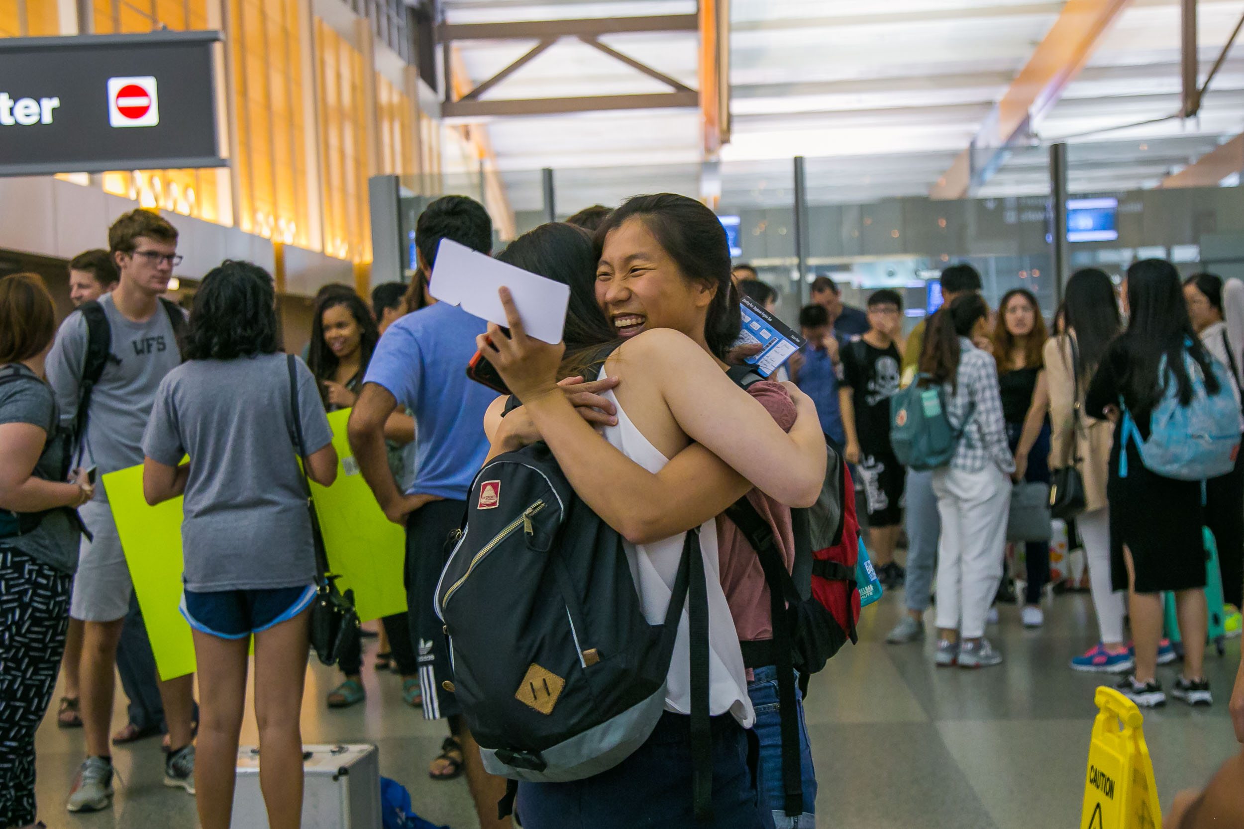 Raleigh Engagement Photographer | G. Lin Photography | Friends hugging by baggage claim