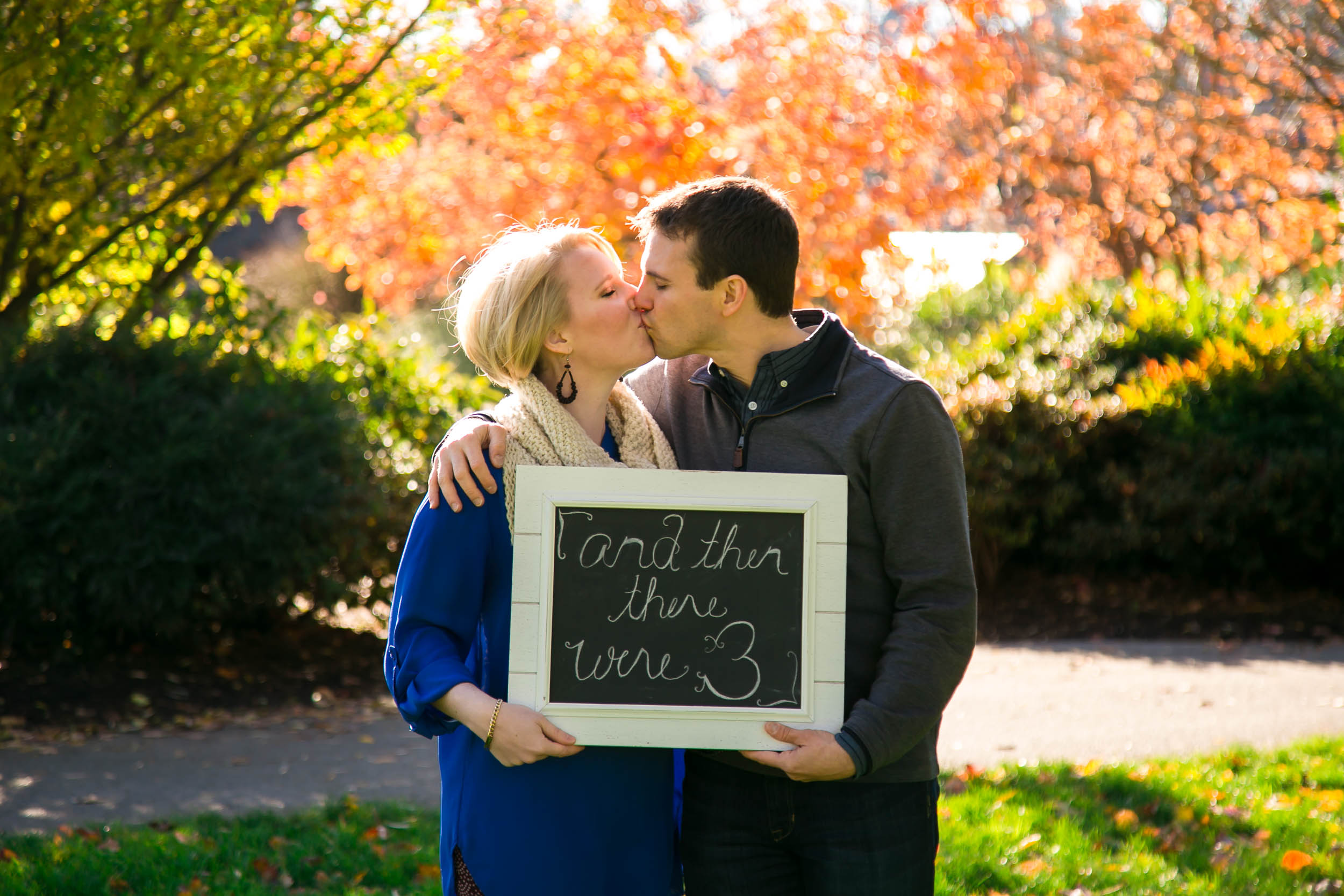 Seattle Family Photographer | G. Lin Photography | Couple holding sign and kissing in Bellevue Park