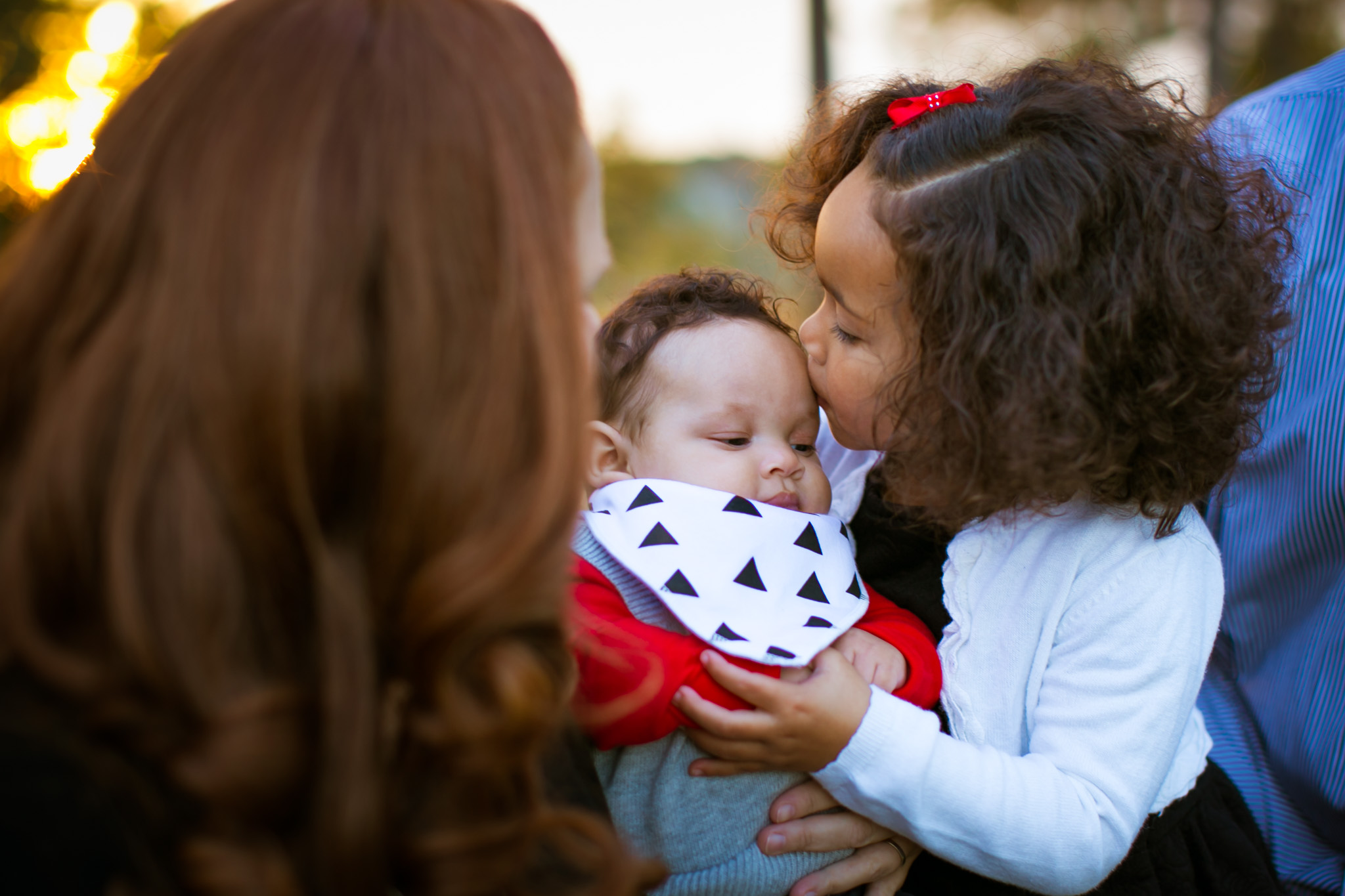 Durham Family Photographer | G. Lin Photography | Girl holding baby brother and kissing him on head