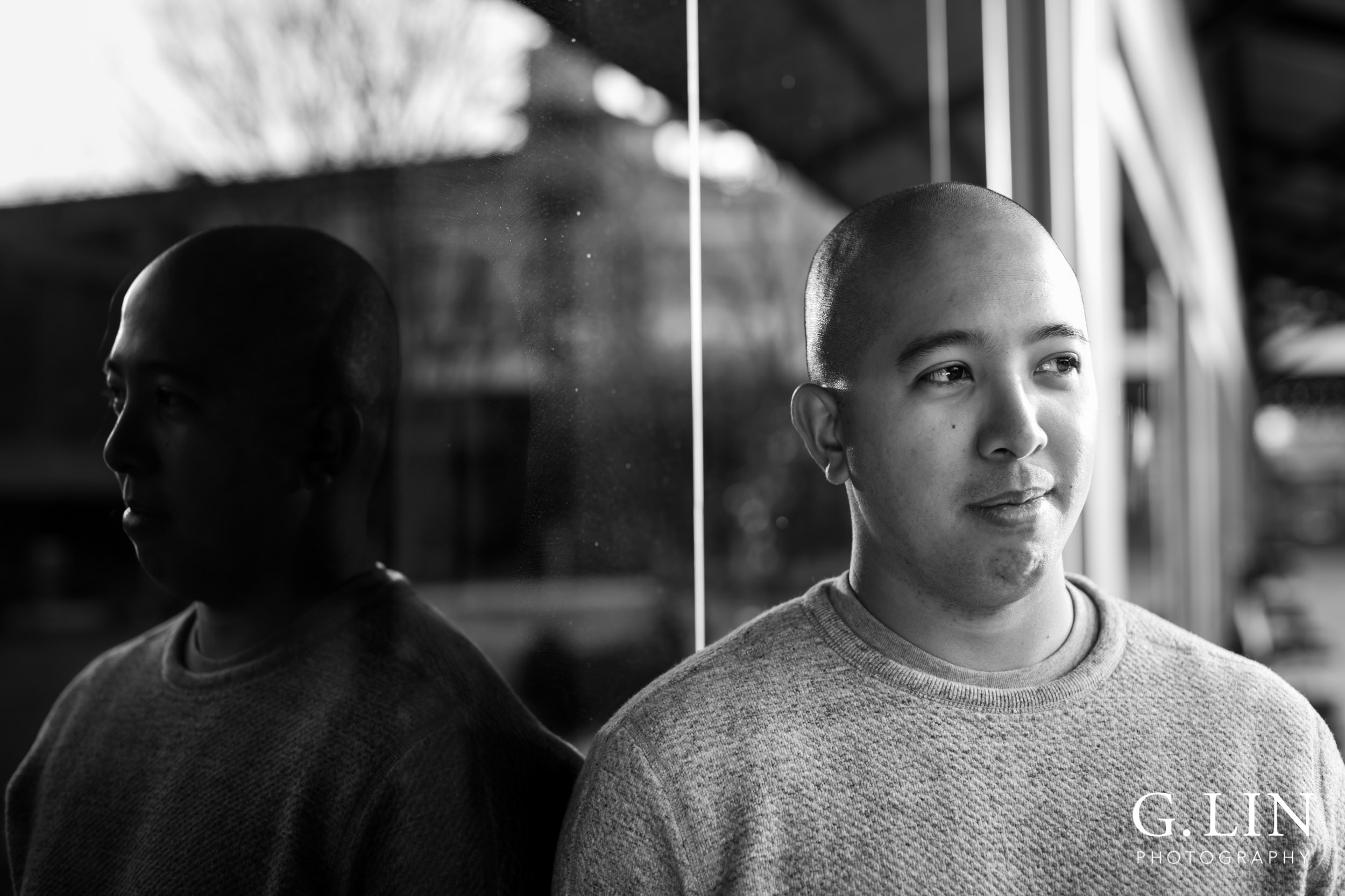 Durham Family Photographer | G. Lin Photography | Black and white photo of man leaning against glass window