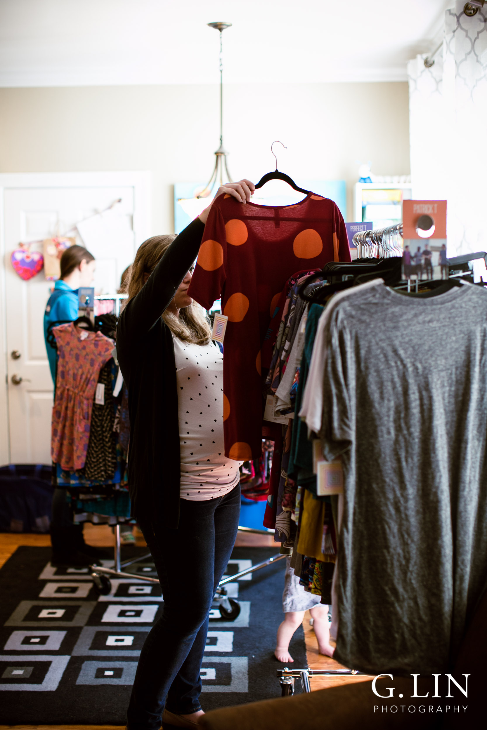 Raleigh Event Photographer | G. Lin Photography | Woman holding dress up next to clothing rack