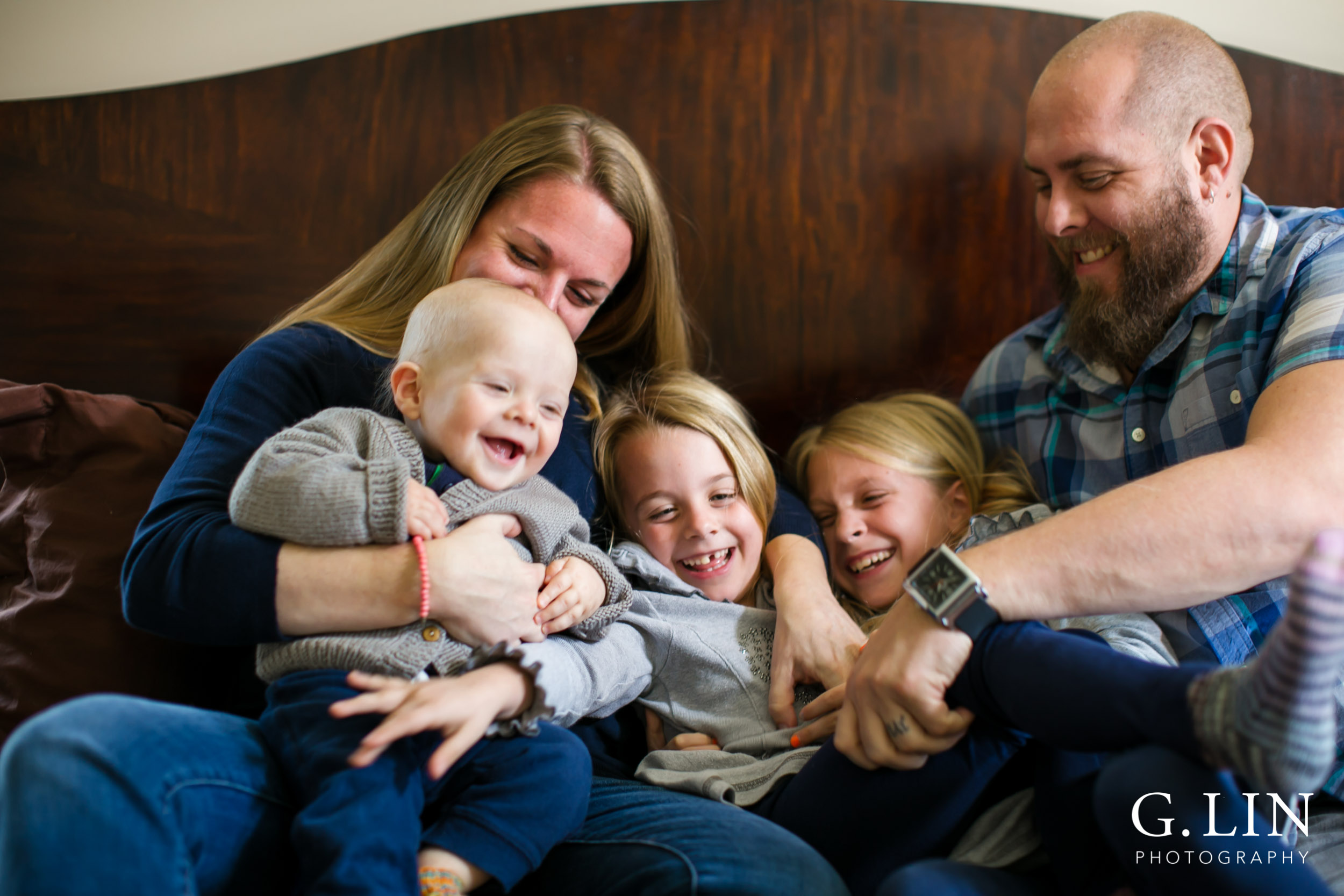 Raleigh Family Photographer | G. Lin Photography | Family sitting on bed and smiling and tickling each other