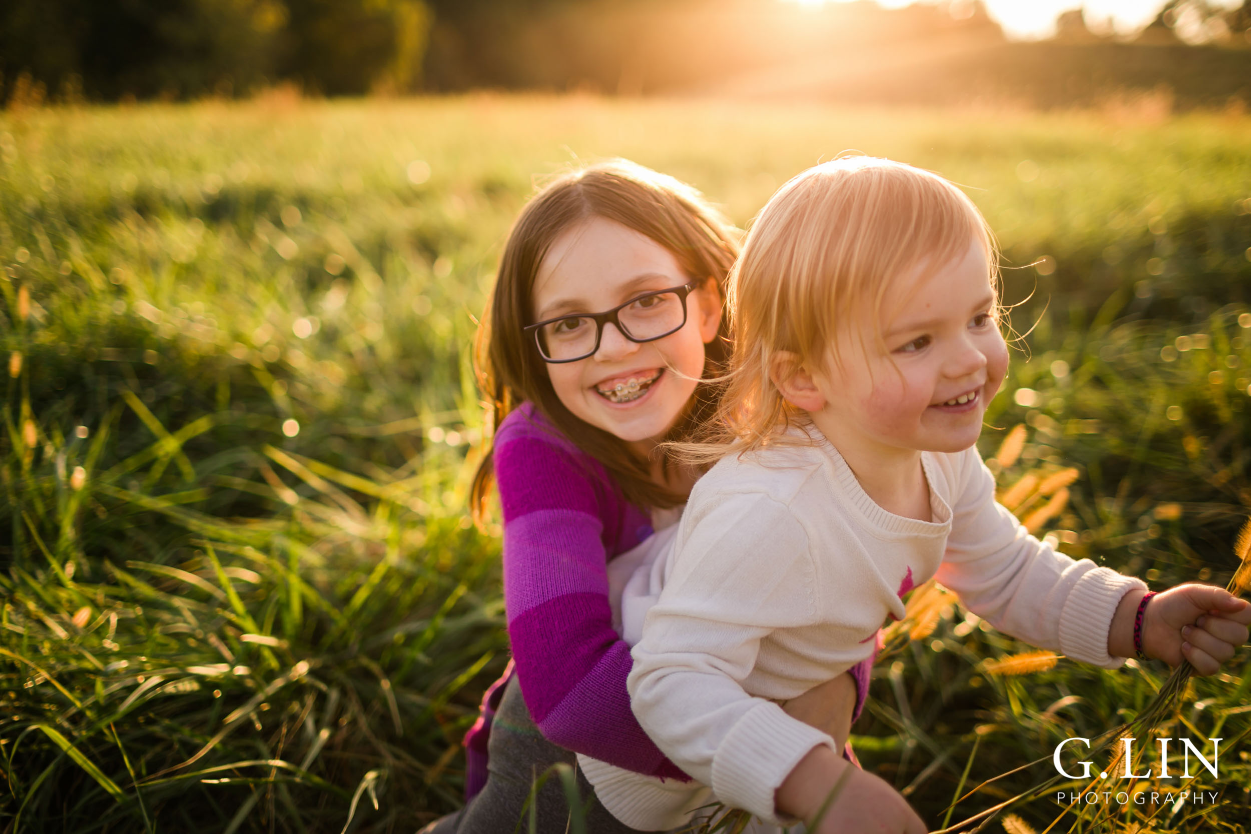 Candid Lifestyle photography of Sisters playing in an open field and laughing | Raleigh Family Photographer | G. Lin Photography