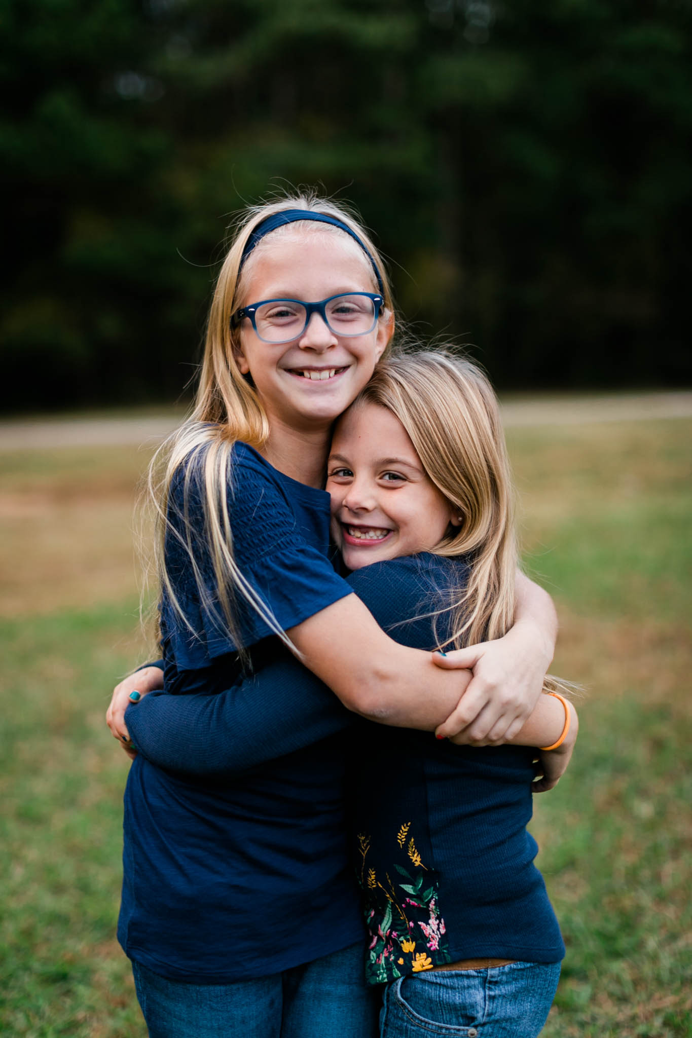 Sisters hugging each other at Umstead Park | Raleigh Family Photographer | By G. Lin Photography