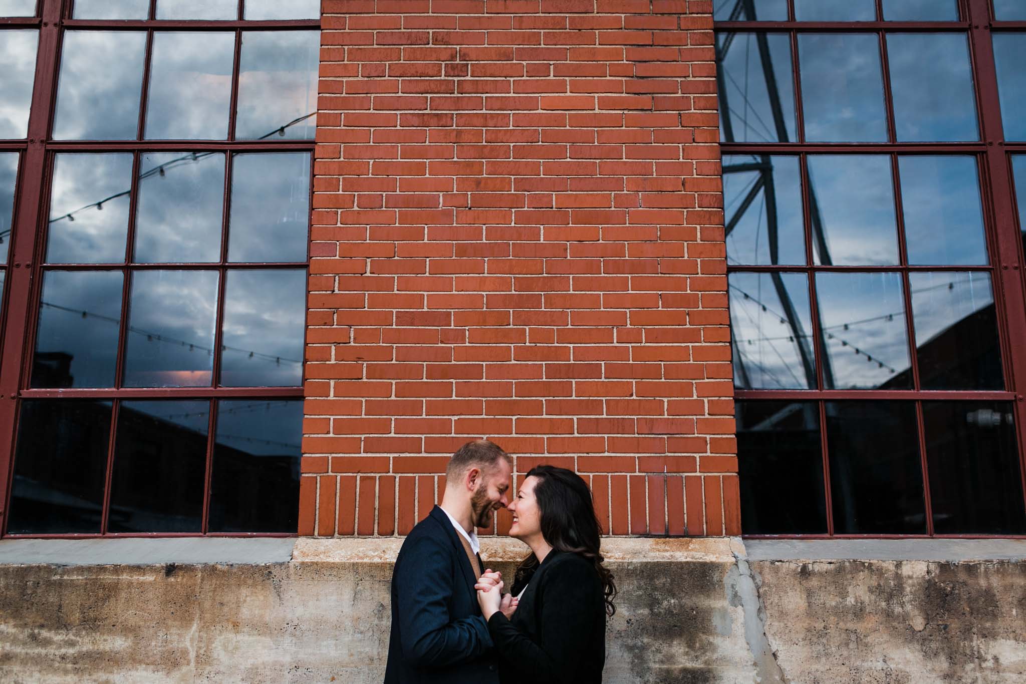 Wide shot of couple outside of brick building | American Tobacco Campus Photography in Durham, NC | By G. Lin Photography