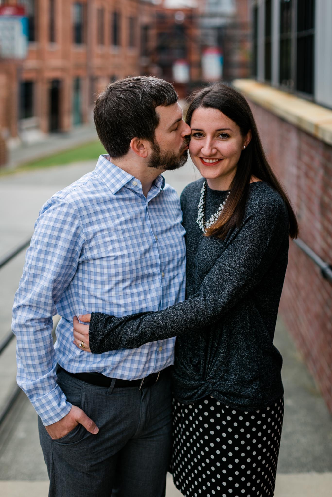 Husband kissing wife on cheek in Downtown Durham | Durham Photographer | By G. Lin Photography