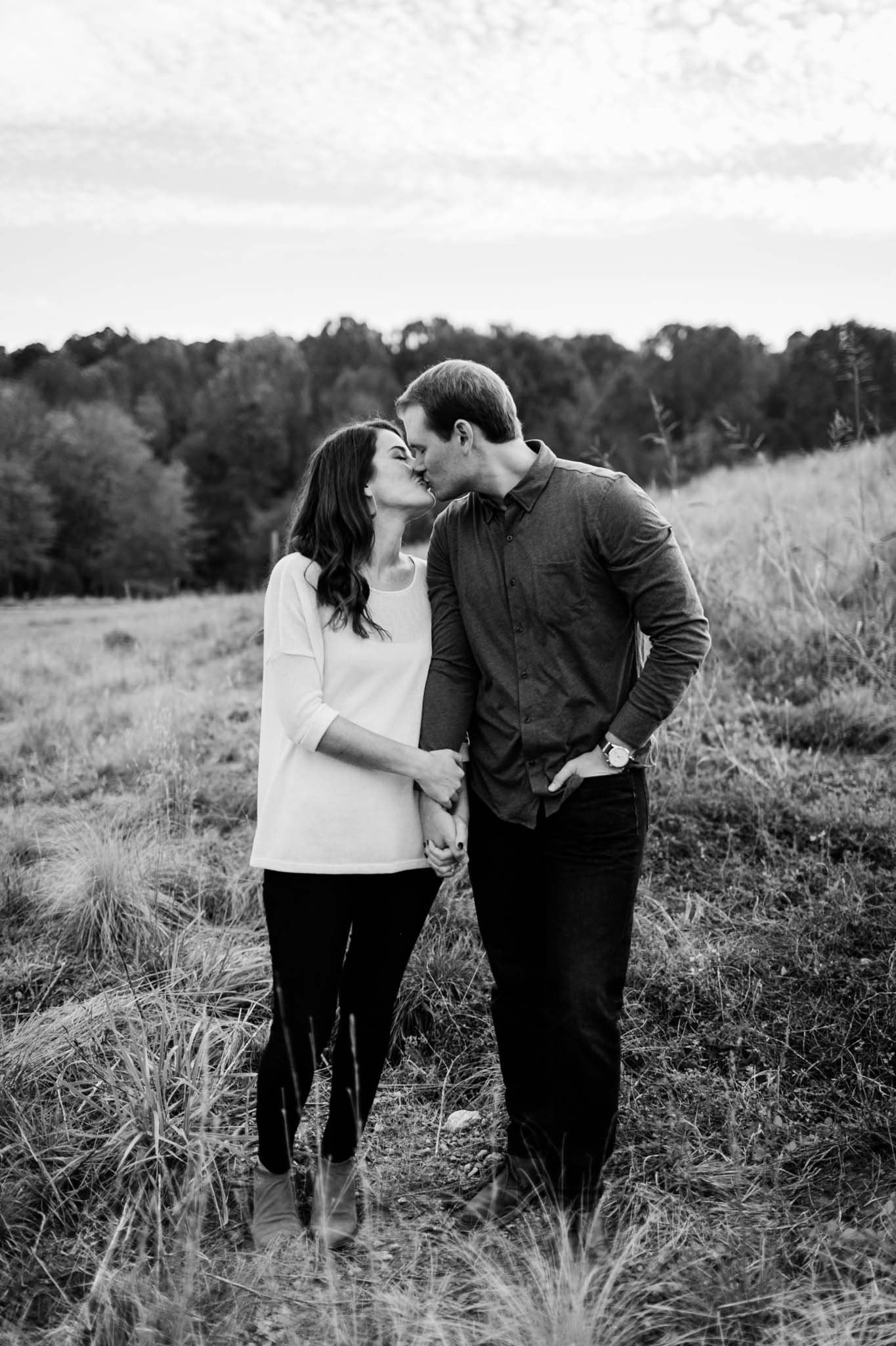 Black and white photo of couple kissing in field | Raleigh Family Photographer | By G. Lin Photography