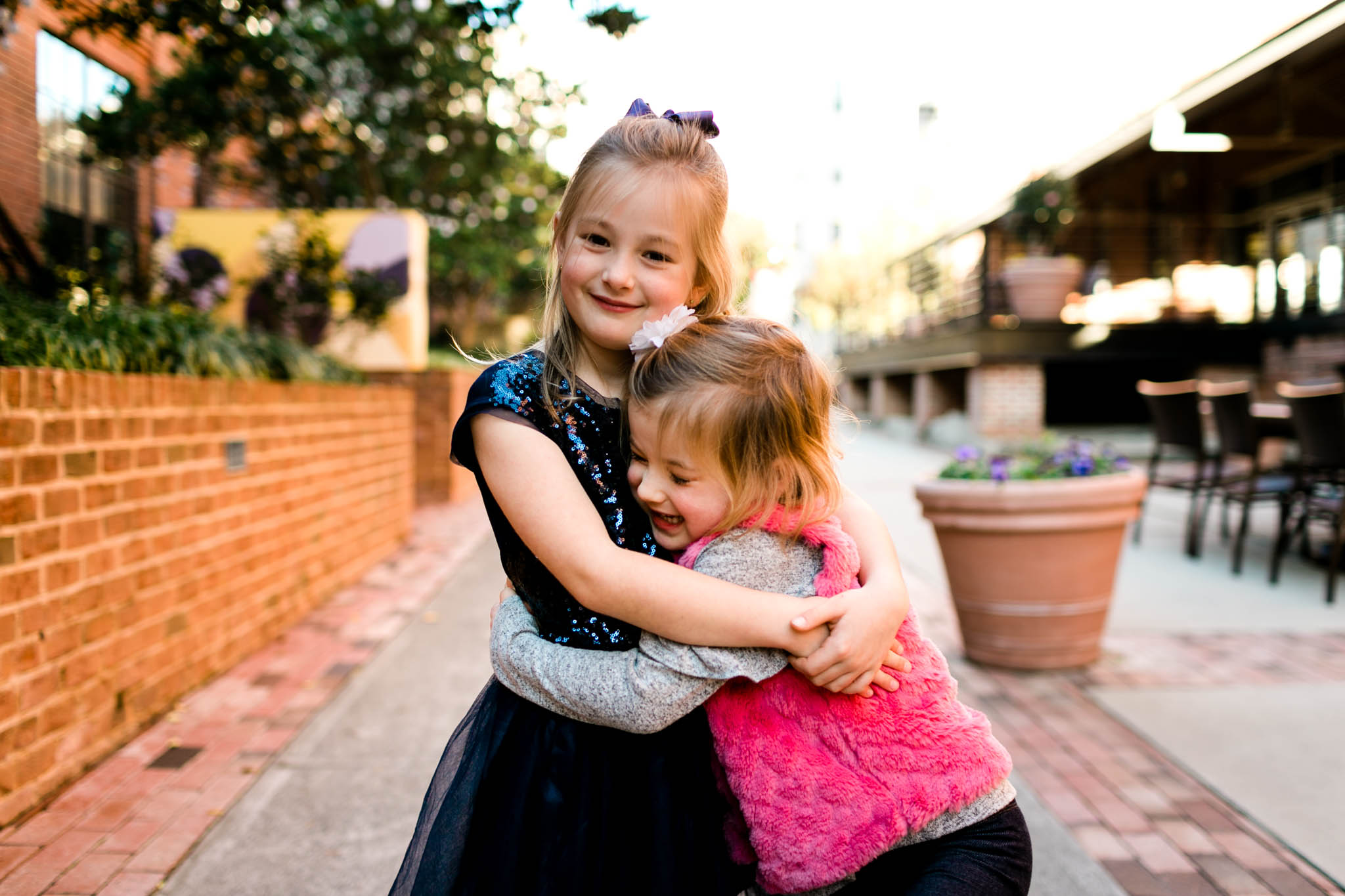 Sisters hugging each other | Durham Family Photographer | American Tobacco Campus | By G. Lin Photography