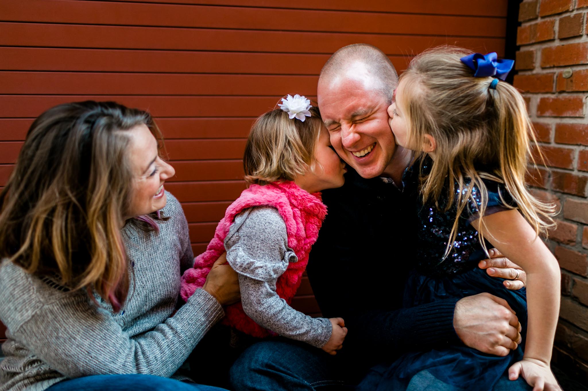 Daughters kissing dad on the cheek | American Tobacco Campus | Durham Family Photography | By G. Lin Photography