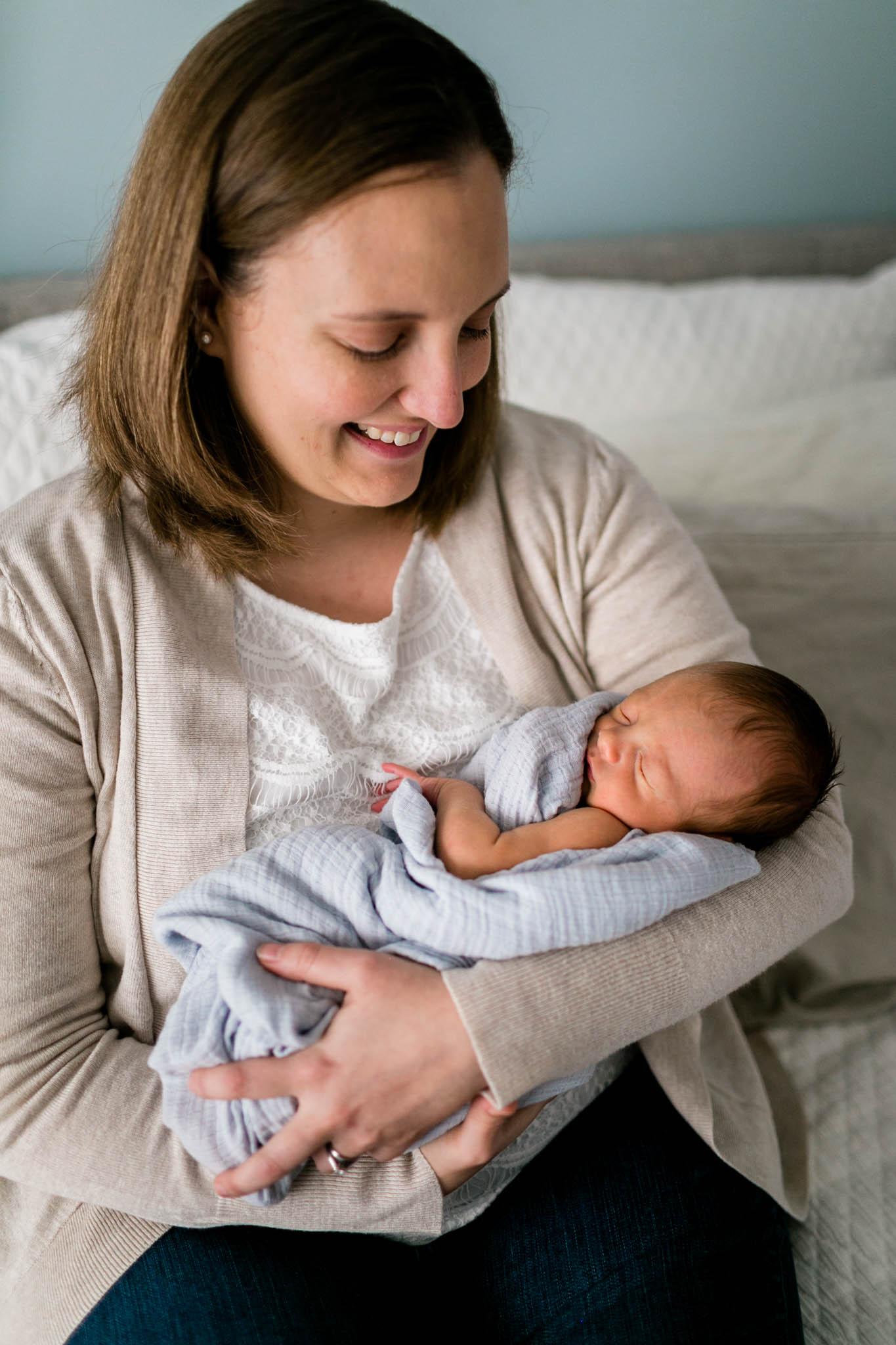 Mother holding baby in arms sitting on bed | Raleigh Newborn Photographer | By G. Lin Photography