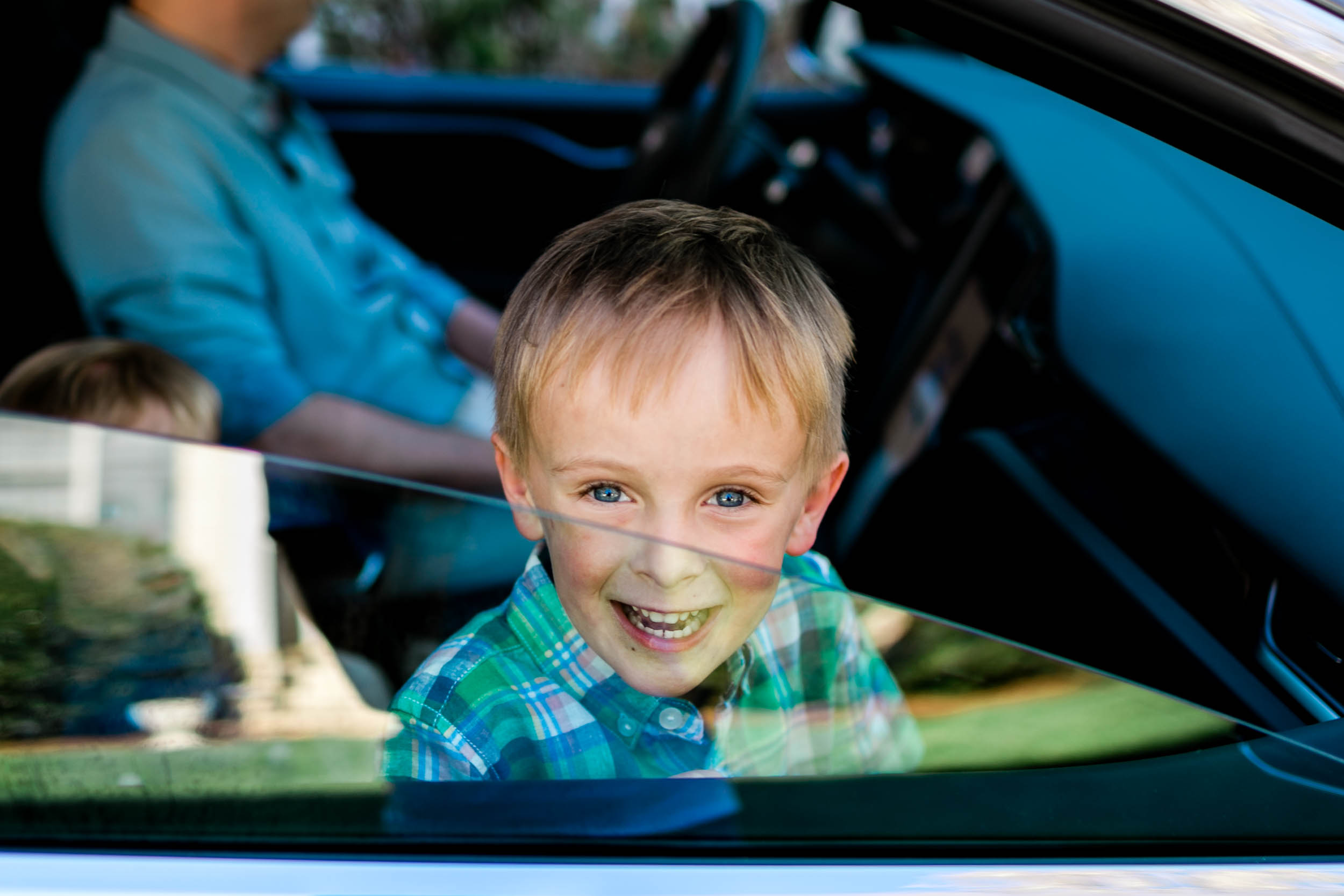 Boy sitting inside of car and smiling | Durham Family Photographer | By G. Lin Photography