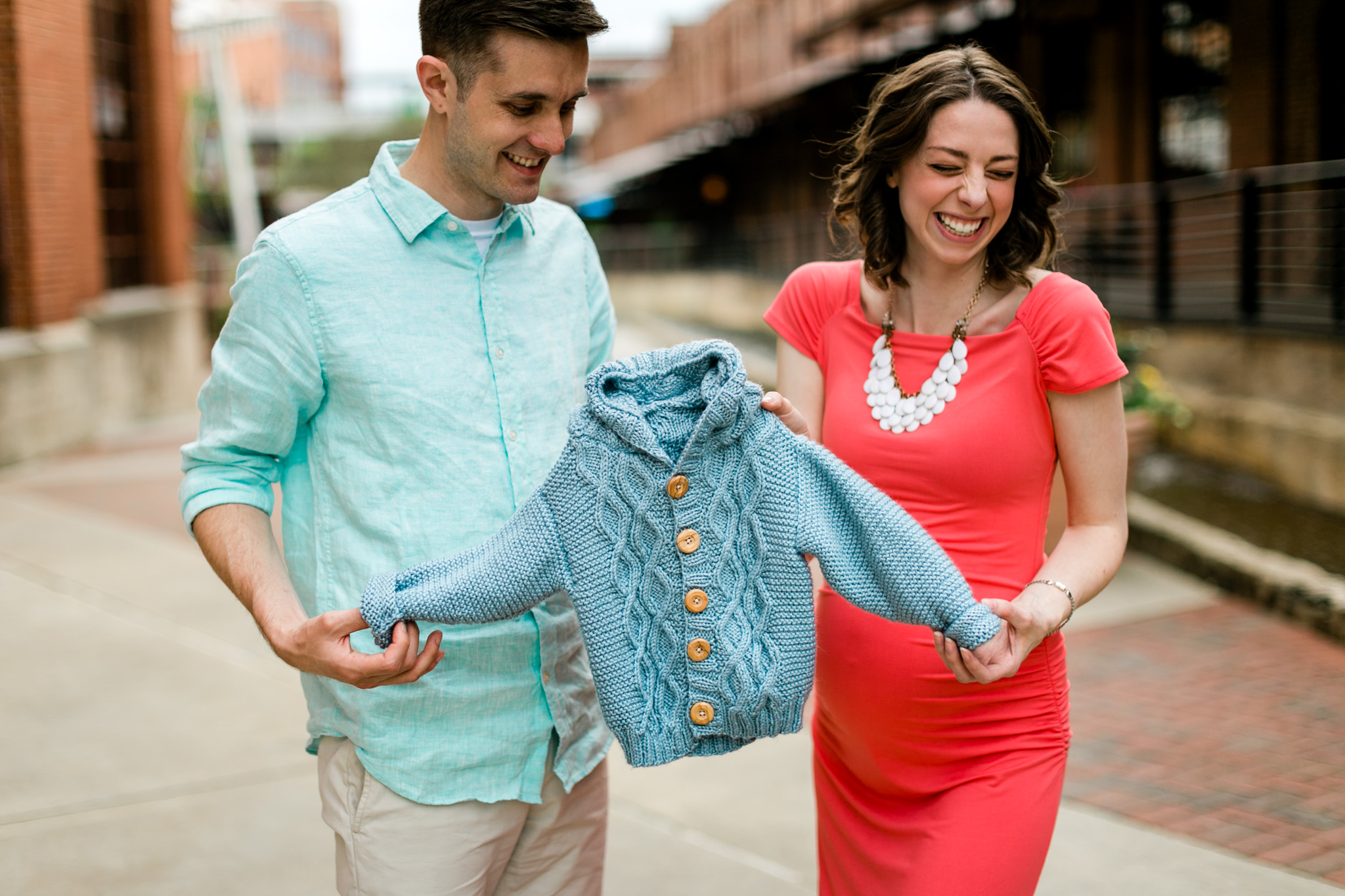 Couple holding baby sweater and laughing | Raleigh Family Photographer