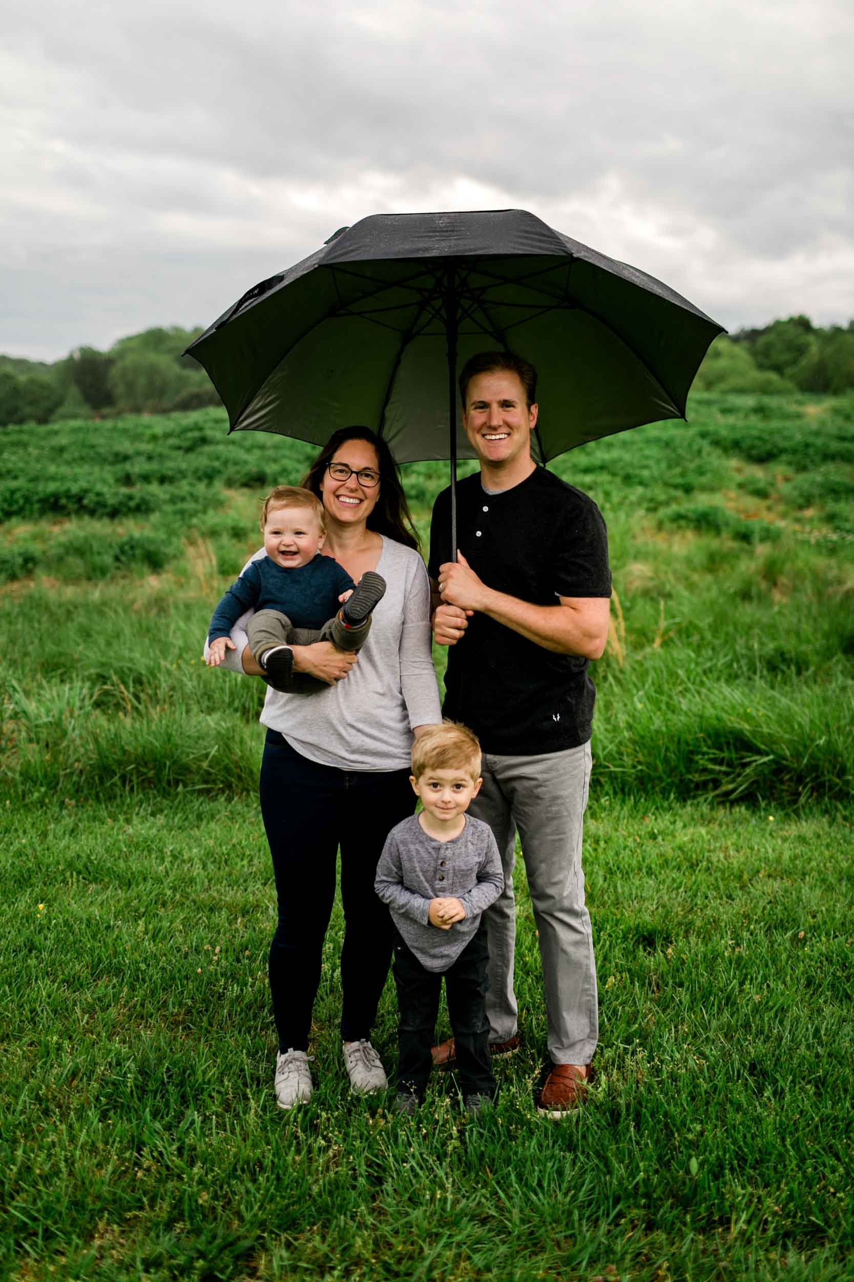 Outdoor spring family portrait | Family holding umbrella during rain | Raleigh Family Photographer | By G. Lin Photography