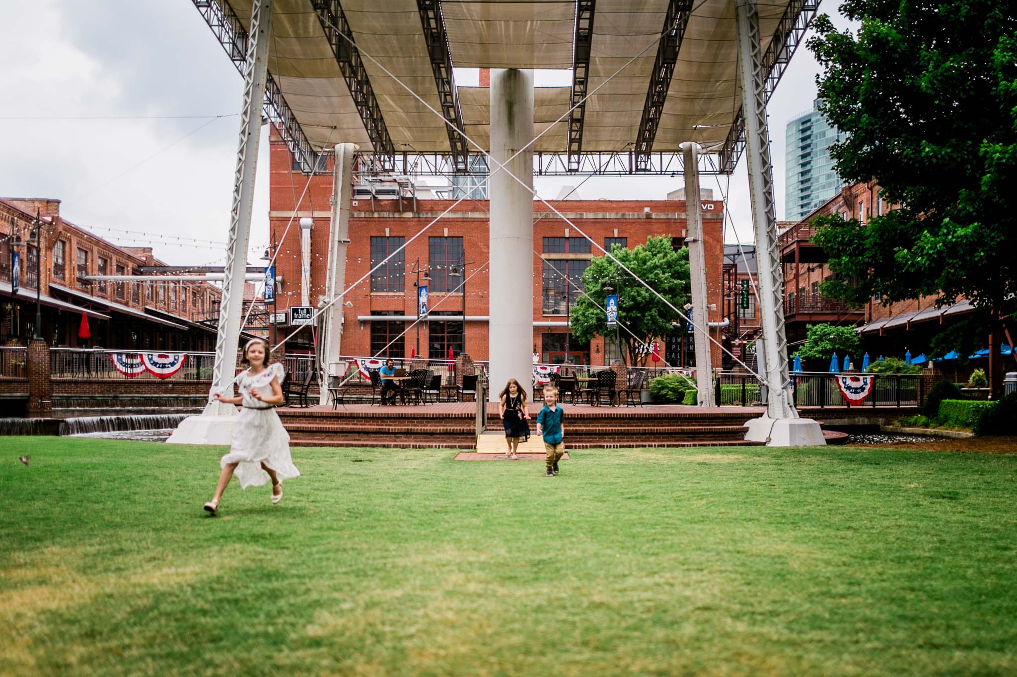Durham Family Photographer | By G. Lin Photography | Candid photo of kids running on grass at American Tobacco Campus