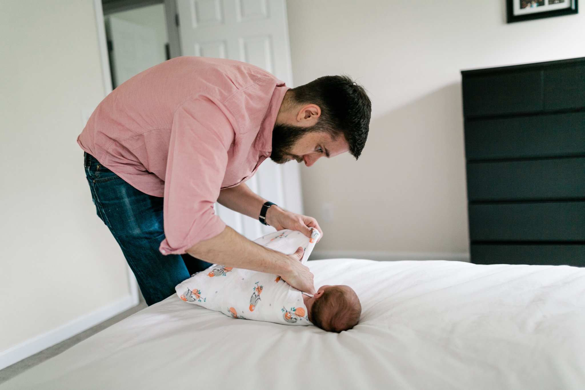 Raleigh Newborn Photographer | By G. Lin Photography | Dad swaddling baby on bed