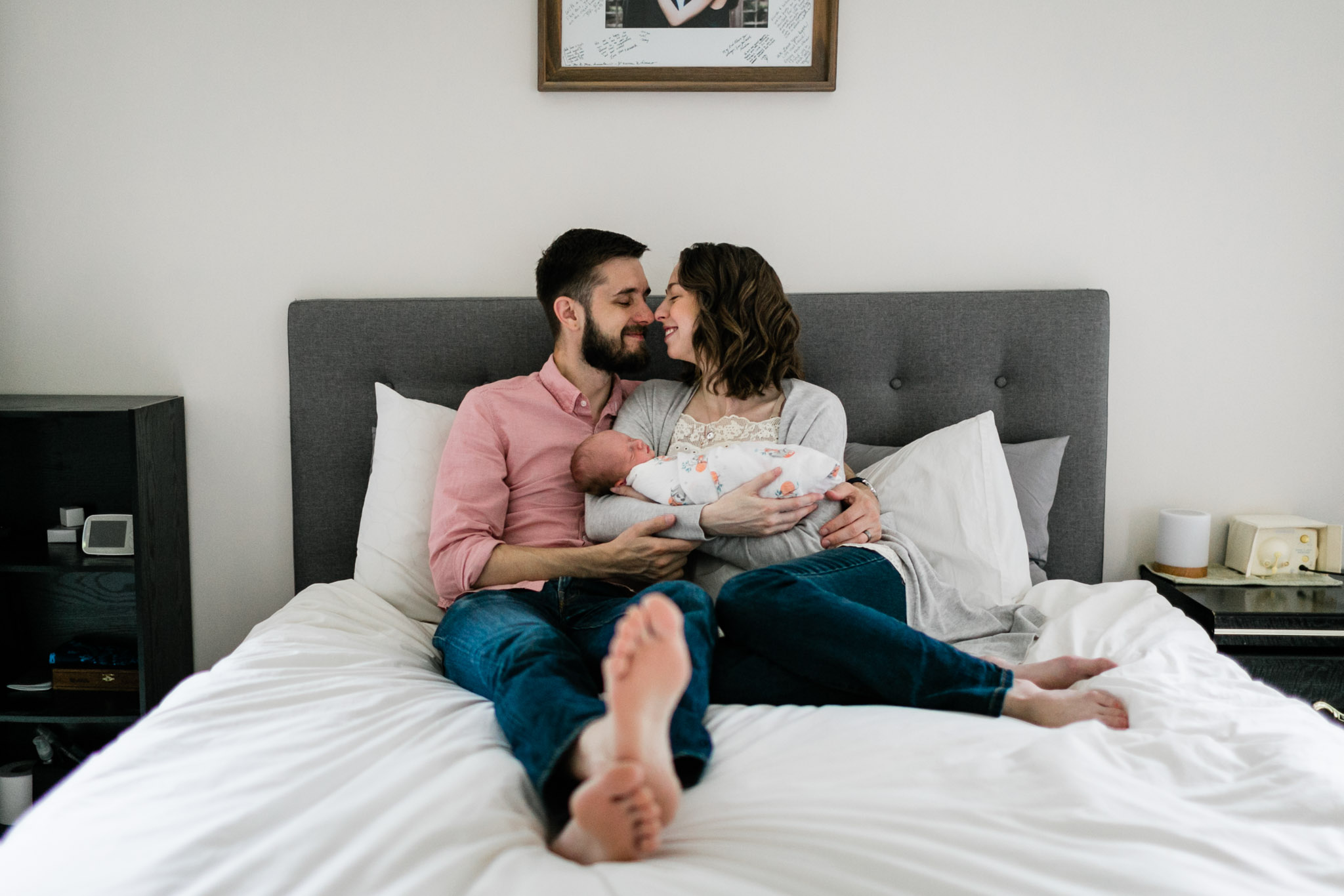 Durham Newborn Photographer | By G. Lin Photography | Parents sitting on bed and holding baby smiling