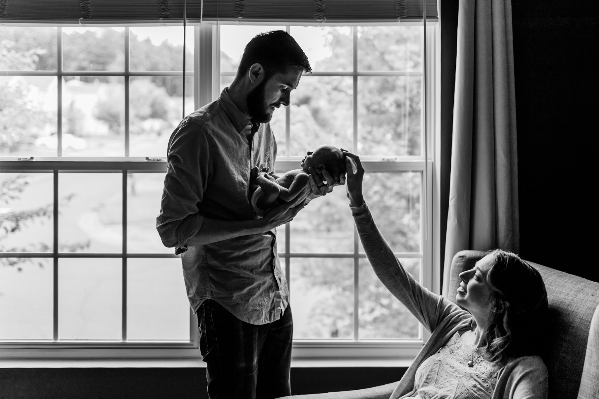 Durham Newborn Photographer | By G. Lin Photography | Black and white lifestyle newborn photography at home | Parents standing next to window