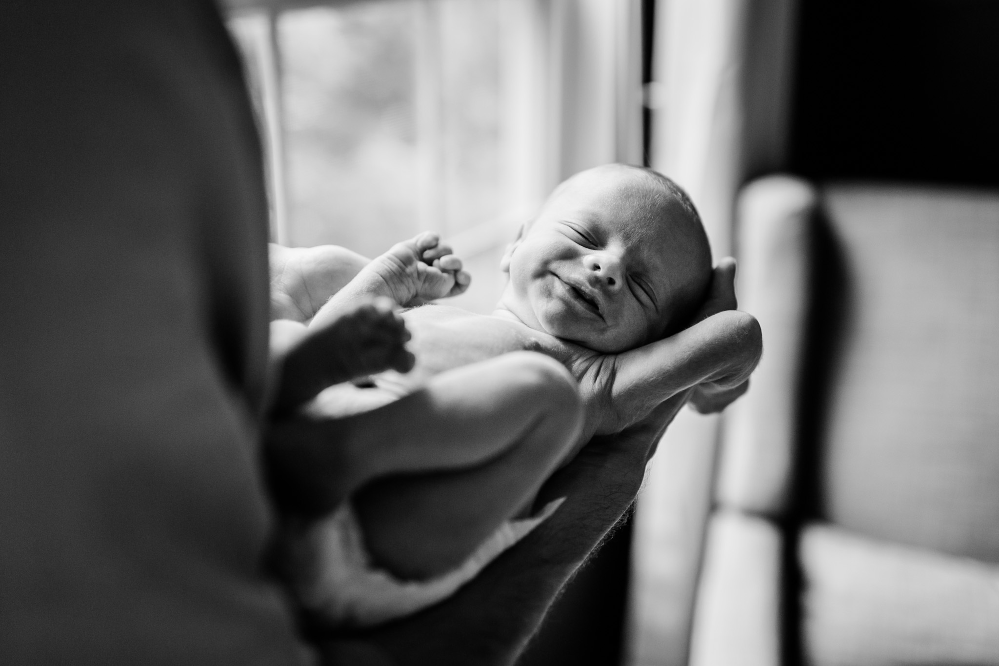 Durham Newborn Photographer | By G. Lin Photography | Lifestyle at home newborn photo shoot | Dad holding baby in hands standing by window