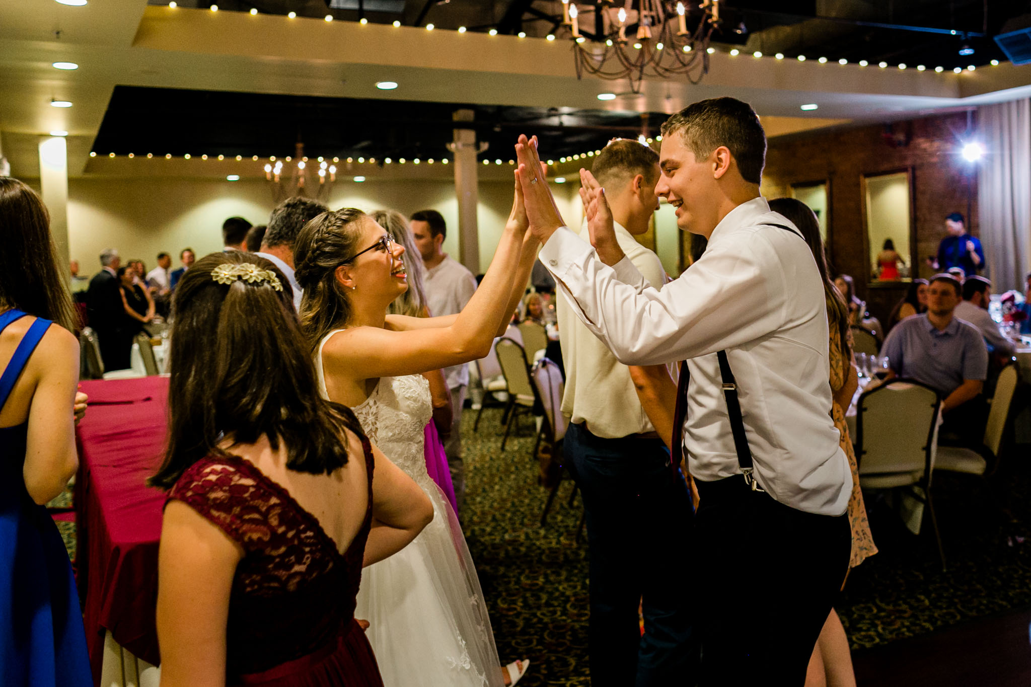 Bride and groom giving each other high fives |People dancing at wedding reception at Royal Banquet Conference Center | Raleigh Wedding Photographer | By G. Lin Photography